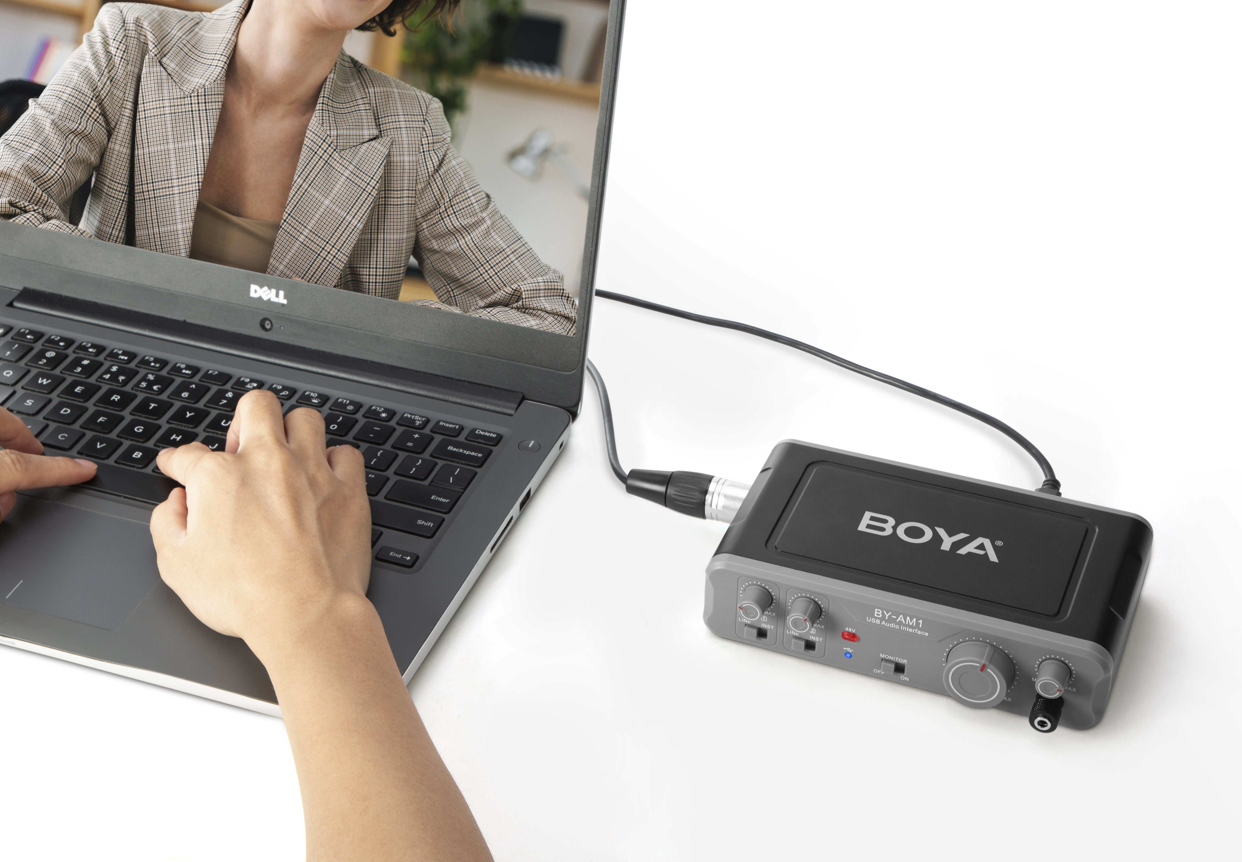 Ordenador portátil con persona usando teclado, conectado a un micrófono e interfaz de audio Boya.