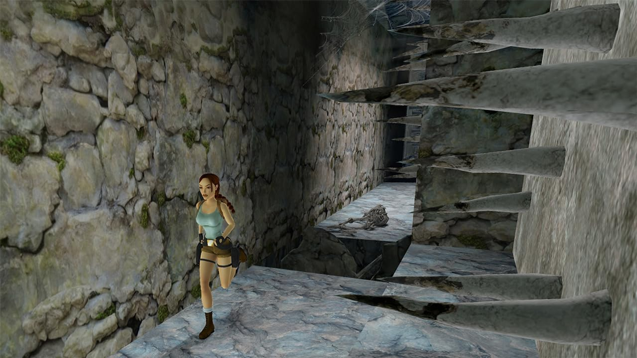 Lara Croft corriendo en una cueva de piedra. Un esqueleto yace en los escalones. La escena es oscura y antigua.
