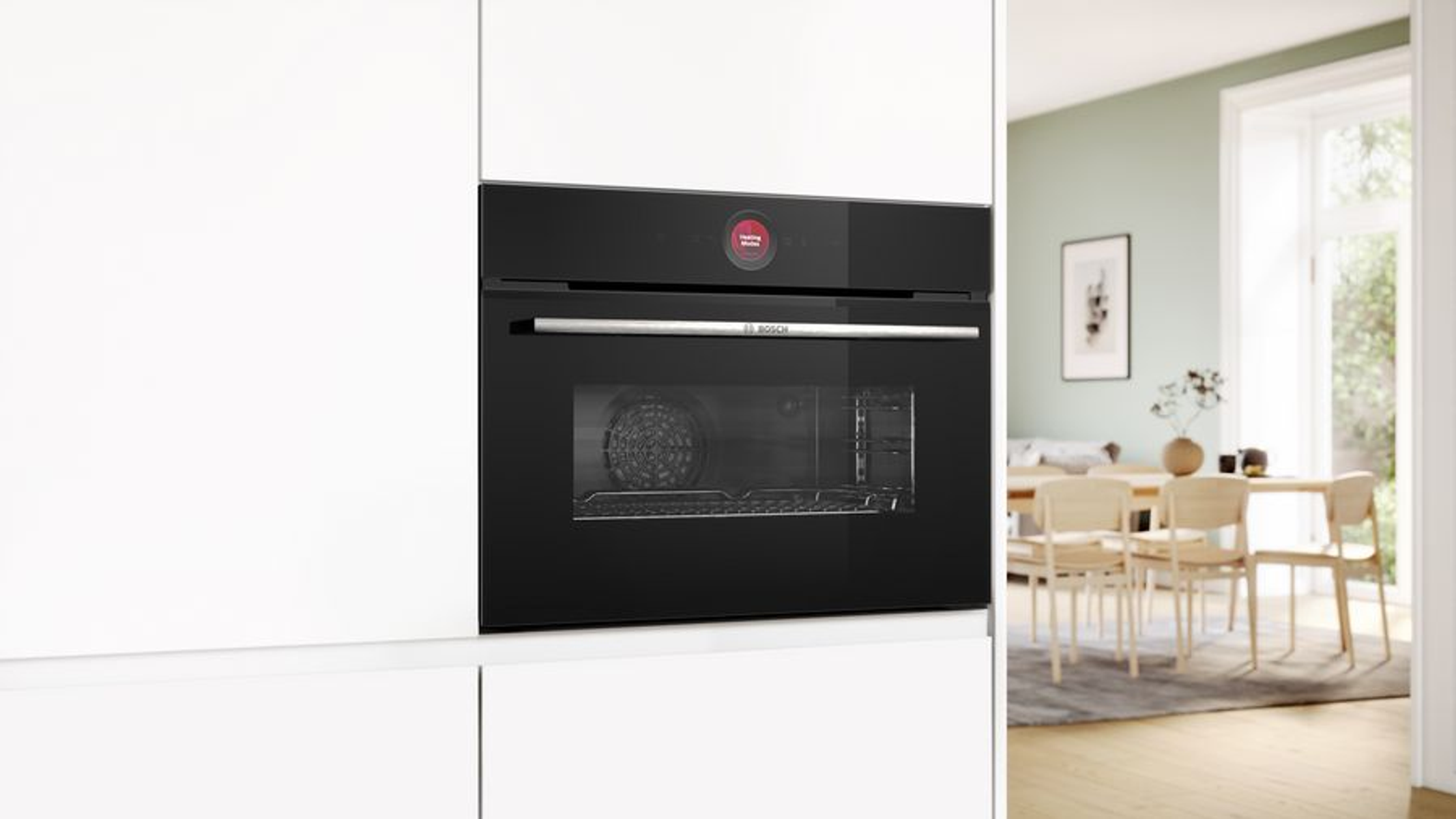 Horno negro empotrado en armarios blancos. Botón rojo de inicio visible sobre la puerta.