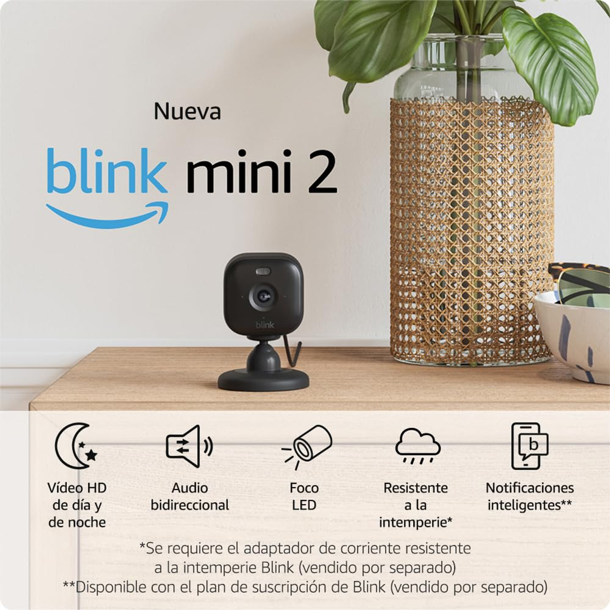 Eine schwarze Blink Mini 2 Sicherheitskamera auf einer Holzoberfläche. Funktionen sind unter der Kamera aufgeführt.