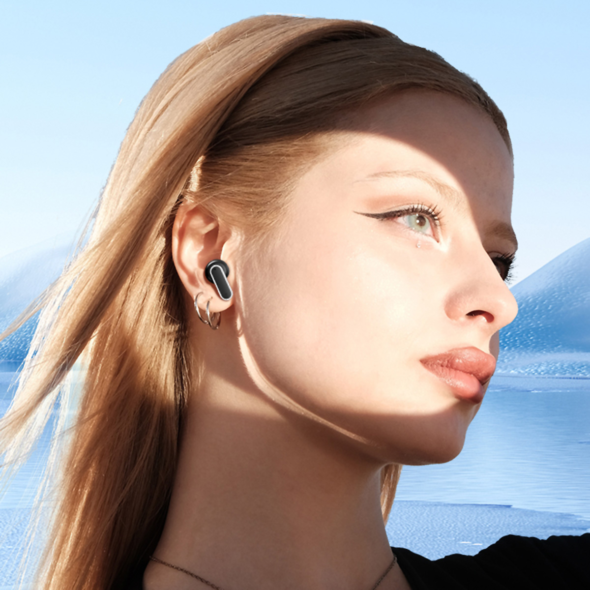 Mujer rubia con auriculares, mirando a la derecha, contra fondo borroso de montañas.
