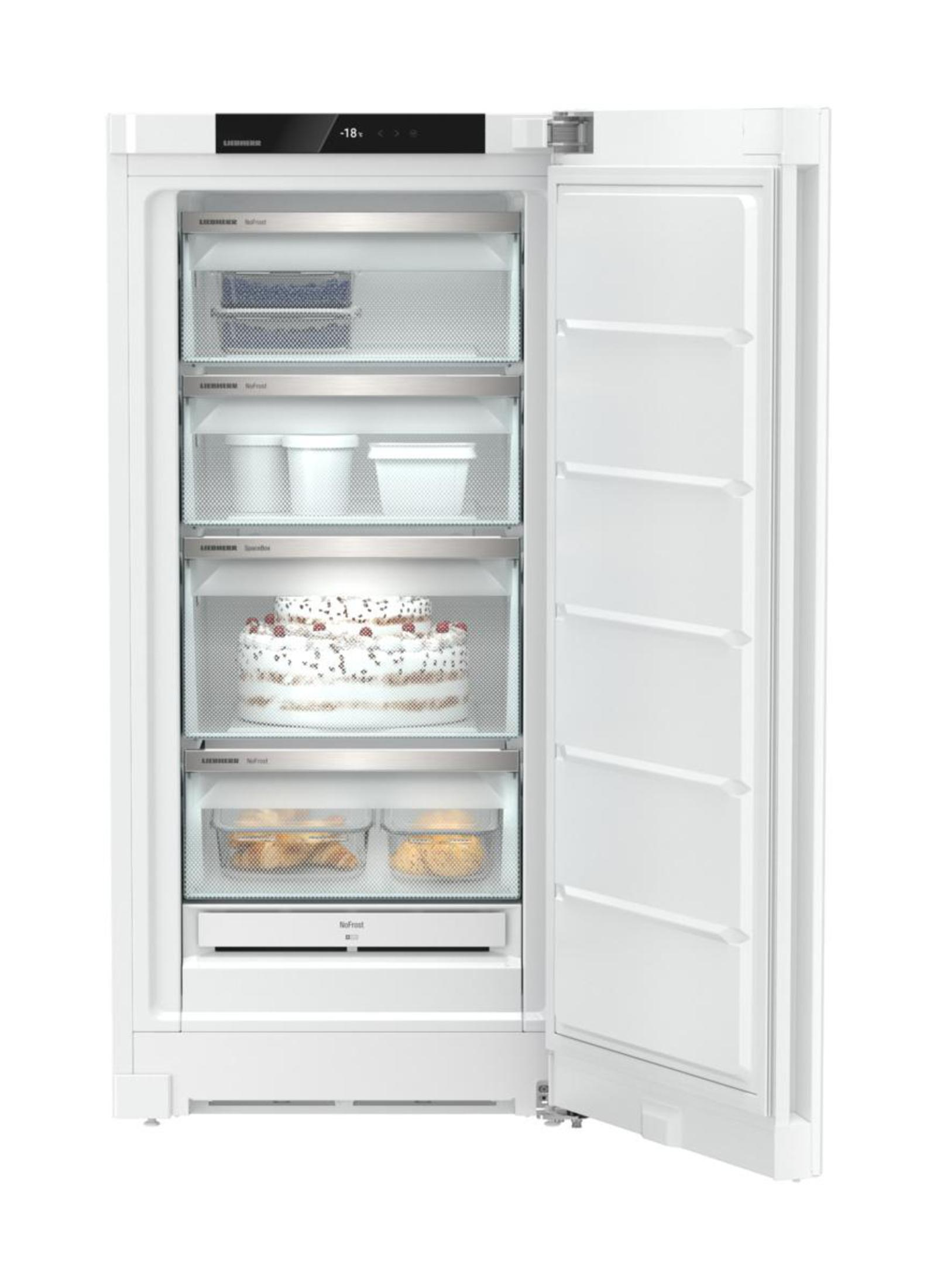 Réfrigérateur blanc ouvert avec des étagères contenant des articles comme un gâteau, des contenants et des aliments.