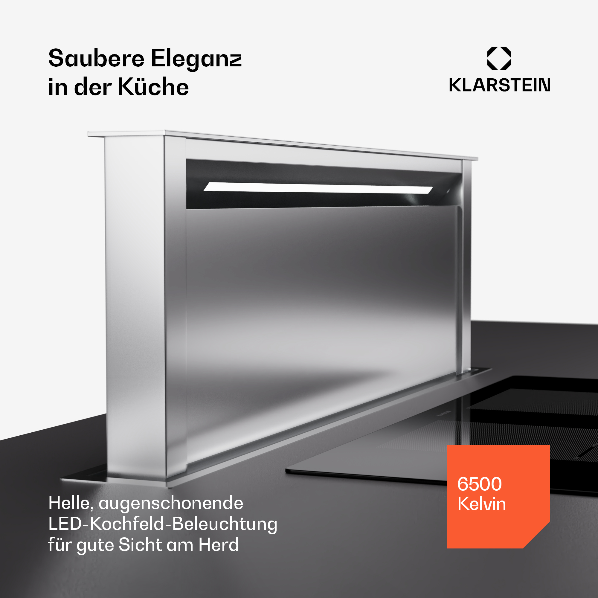 Cappa da cucina moderna con luce. Ha una finitura argentata e un piano cottura nero sotto.