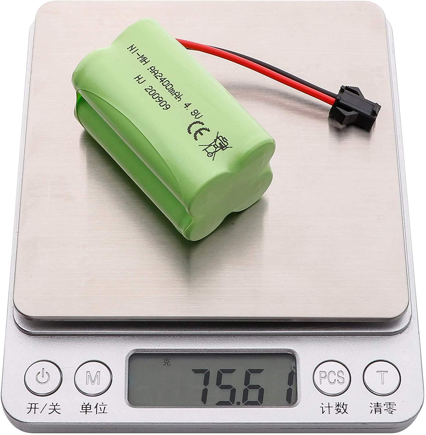 Grüne Batterie auf Waage mit 75,6, schwarzen und roten Drähten.
