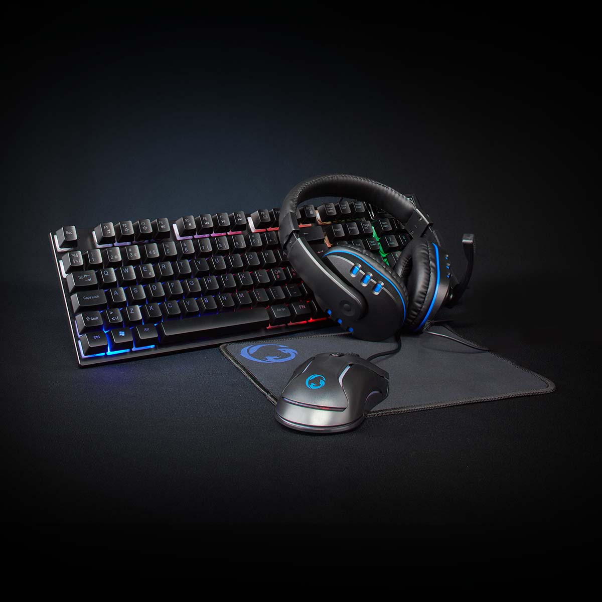 Clavier, casque, souris et tapis noirs sur surface noire. Le clavier a des lumières colorées.