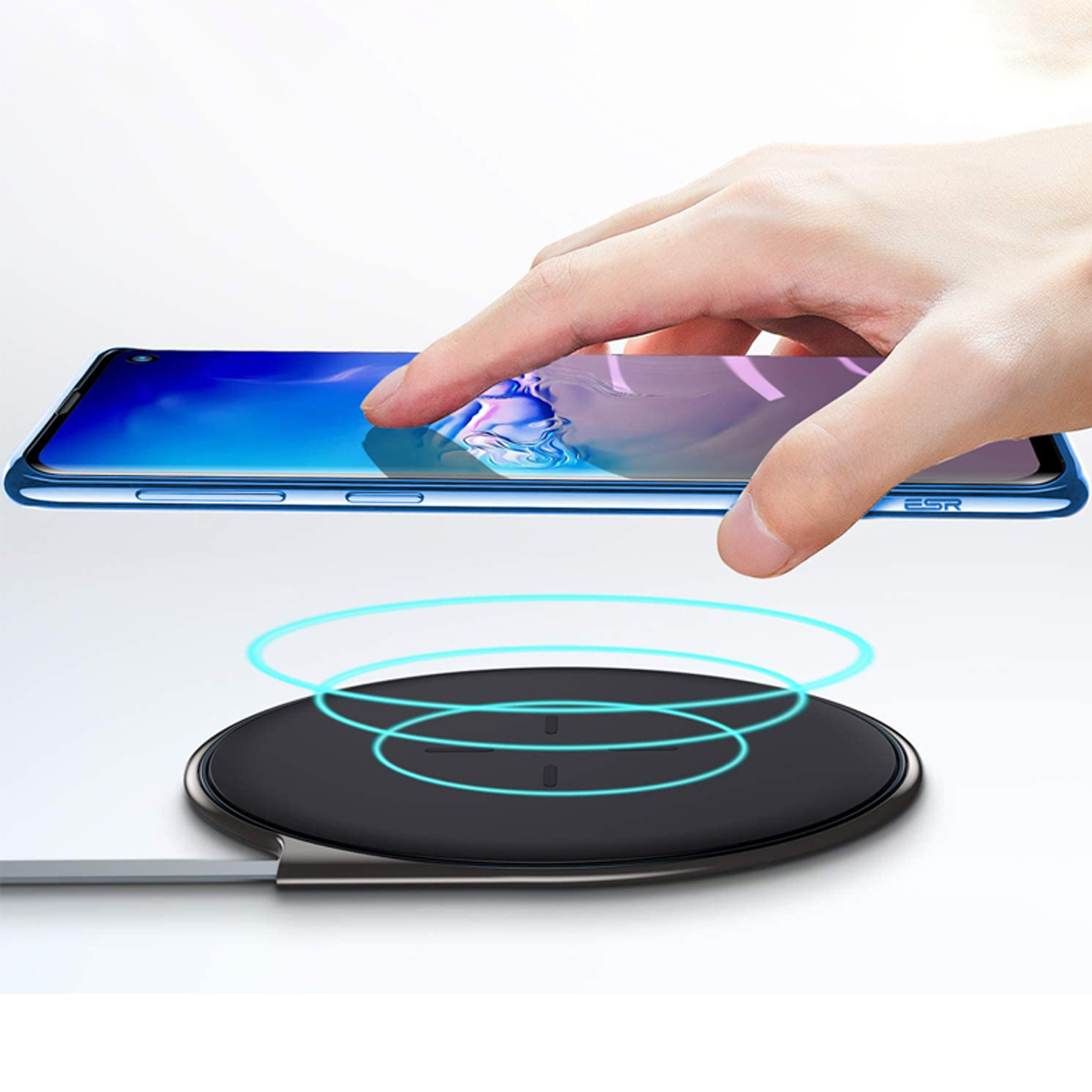 Hand berührt blaues Telefon auf kabellosem Ladegerät. Ladegerät schwarz mit blauen Ringen.