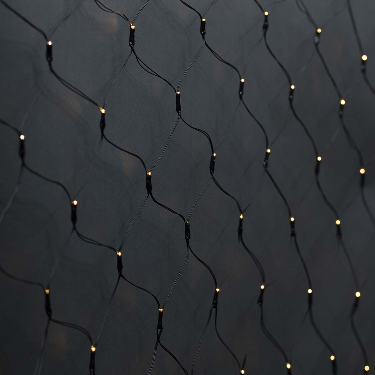 Primo piano di una rete nera con piccole luci gialle, su sfondo scuro, che crea un effetto decorativo.