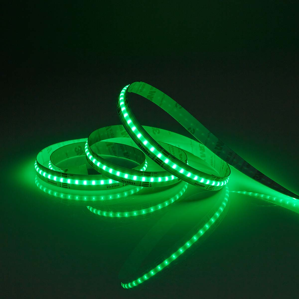 Ein grüner LED-Streifen, aufgerollt, mit hellen Lichtern. Er liegt auf einer reflektierenden Oberfläche.