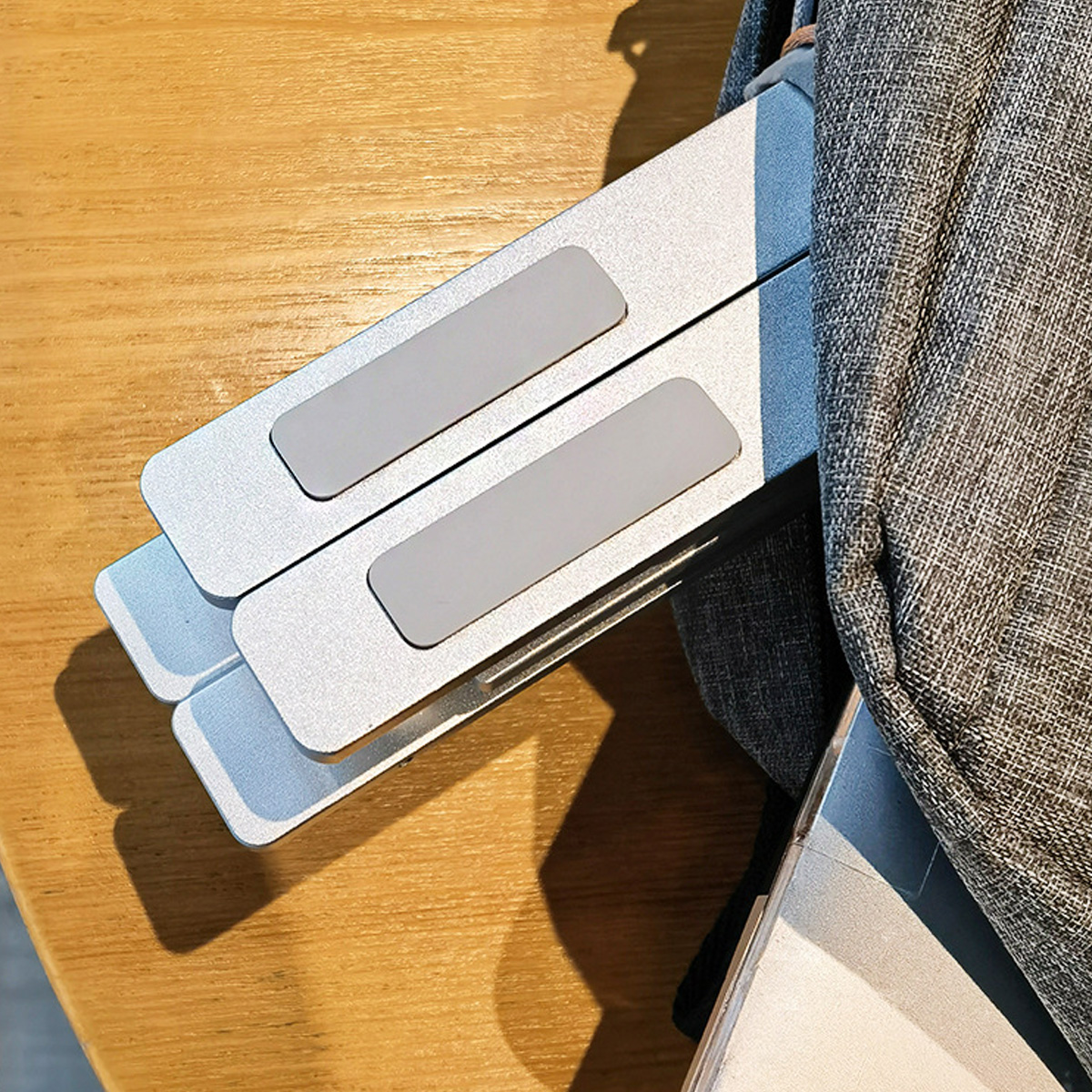 Gefalteter silberner Laptopständer in einer grauen Tasche.