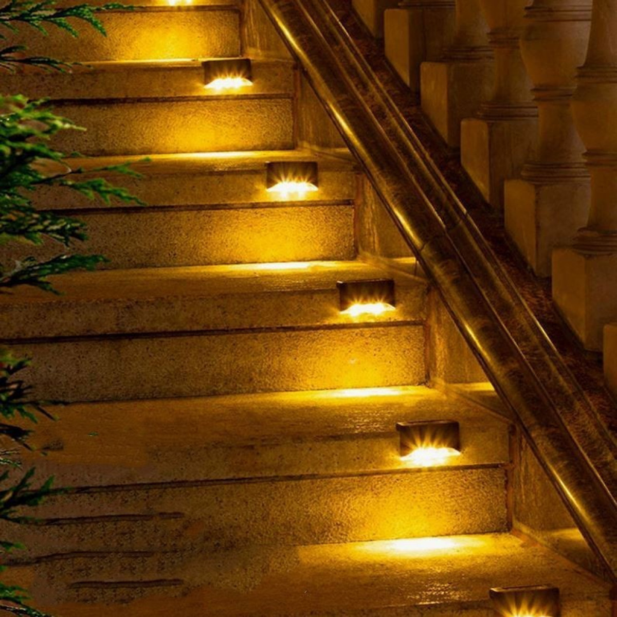 Außentreppe, beleuchtet von kleinen, eingelassenen Lichtern. Die Lichter sind gelb. Die Treppe hat einen Holzhandlauf.