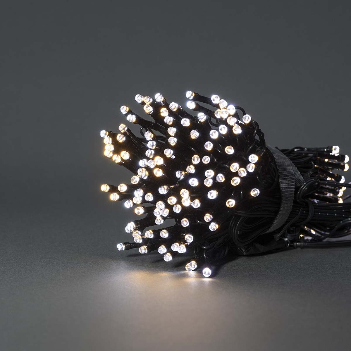 Bundel witte en gele LED-slingerlichten. Draden zijn zwart, op een donkergrijze achtergrond.