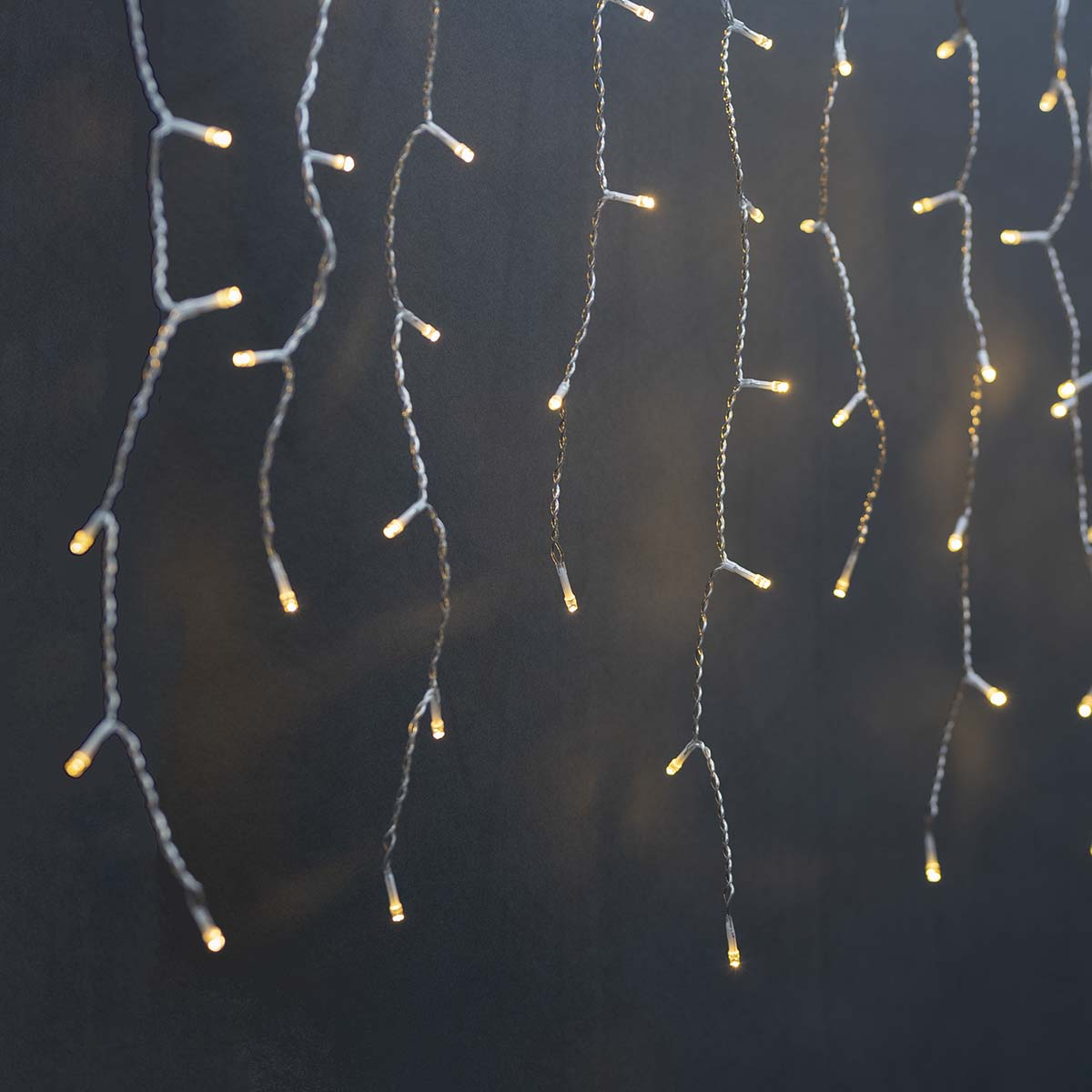 Światła zwisające z ciemnej ściany z maleńkimi ciepłymi światłami.