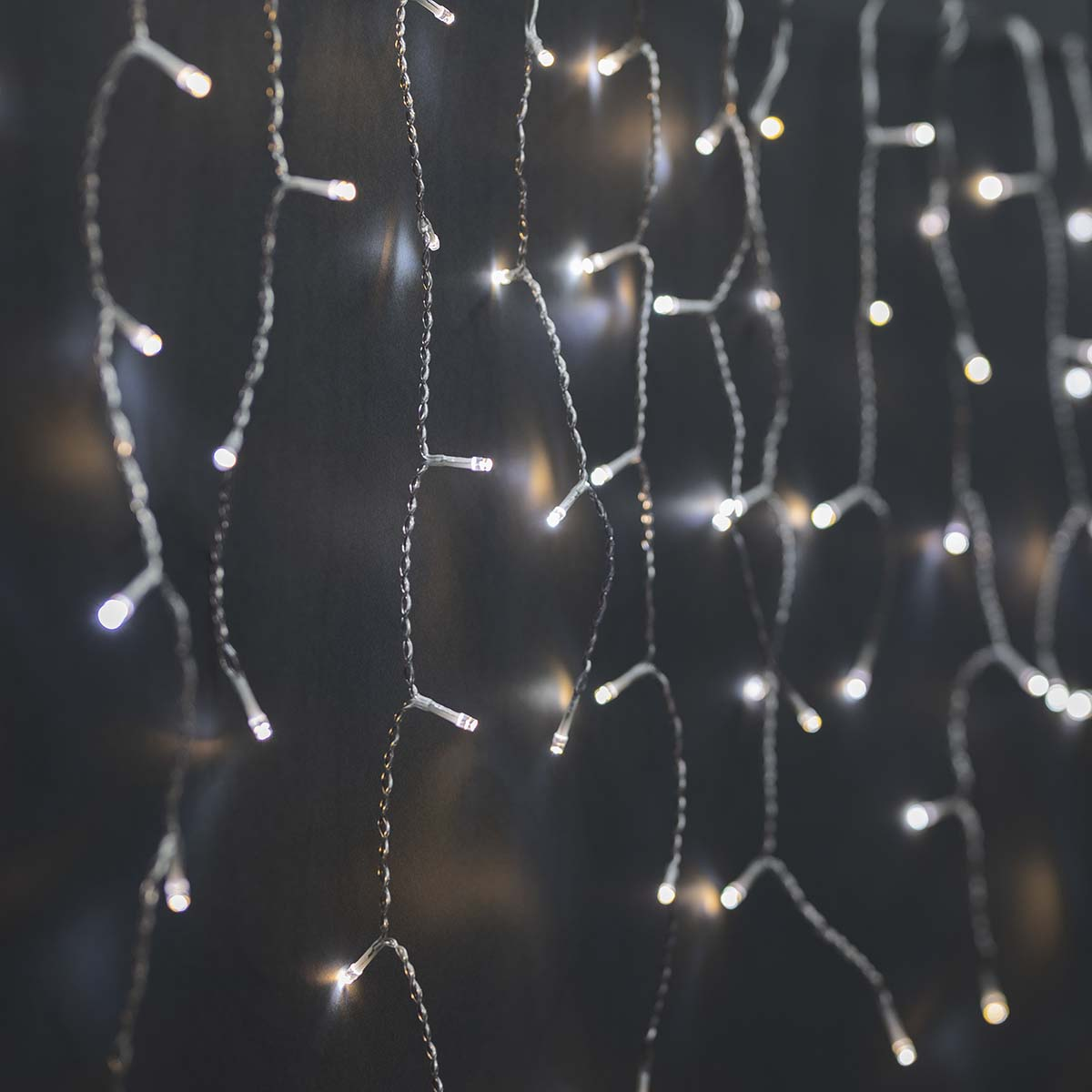 Szereg białych lampek choinkowych wiszących na ciemnym tle.