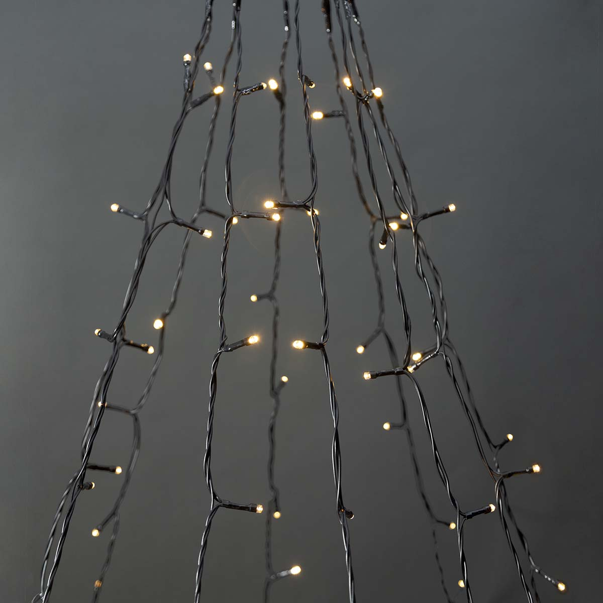 Close-up van kerstverlichting die een boomvorm vormt. De lichten zijn warmwit, op zwarte draden.