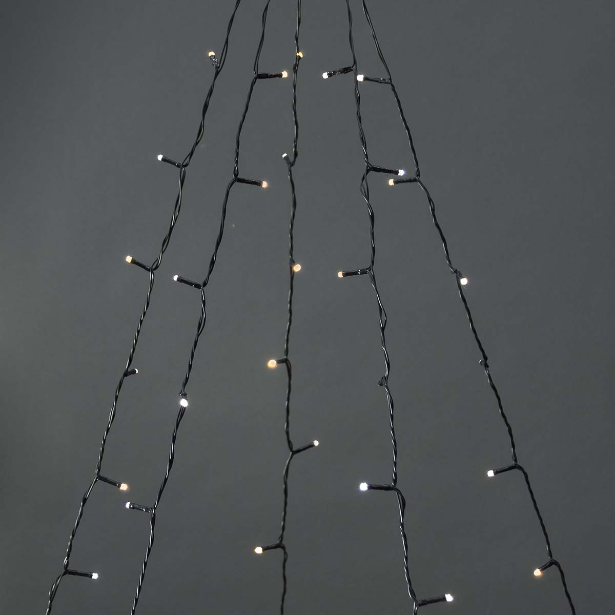 Close-up van kerstverlichting. De lichten zijn warmwit, op zwarte draden. De achtergrond is donkergrijs.