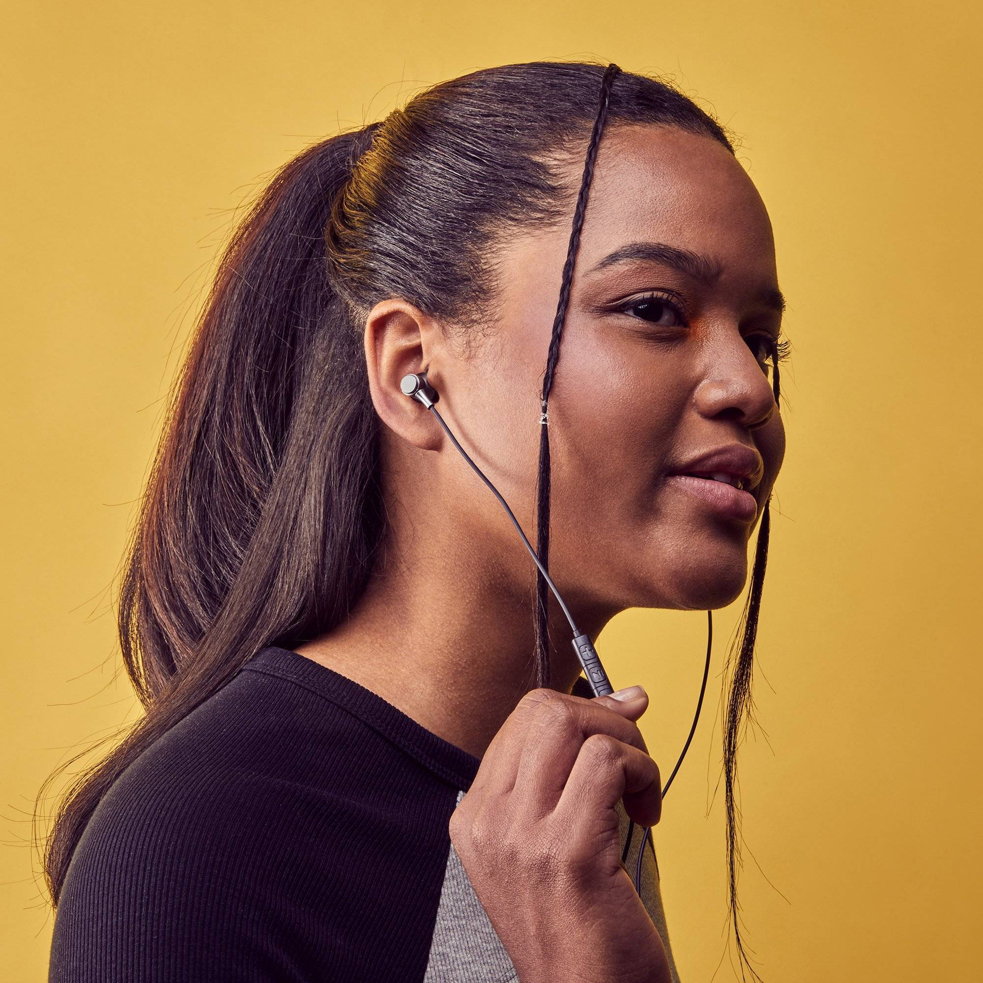 Una joven con cabello negro usando auriculares, mirando hacia la izquierda.
