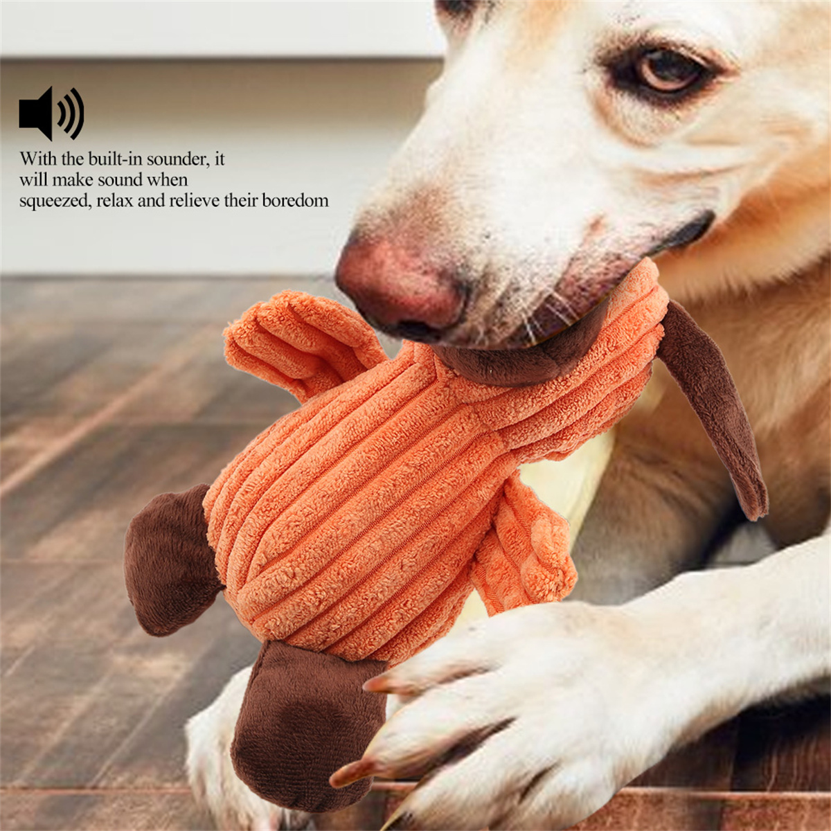 Hund hält ein Plüschhundespielzeug. Spielzeug ist orange und braun.