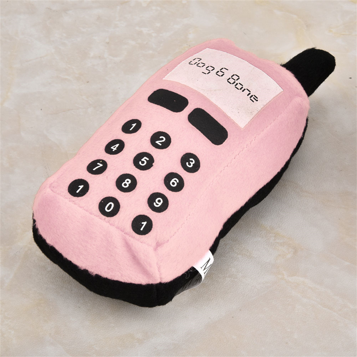 Rosa Hundespielzeug in Telefonform. Schwarze Knöpfe und Hörer. Text: Dogs & Bone.