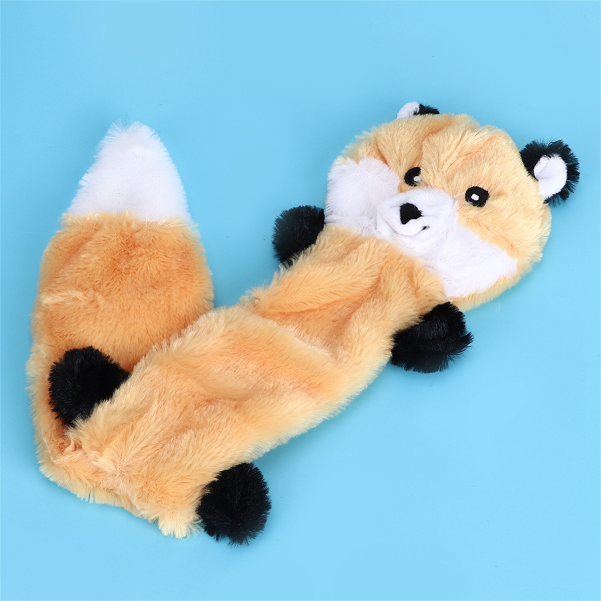 Fuchs-Plüschtier auf Blau. Oranger Körper, weiße Brust/Schwanz, schwarze Pfoten/Ohren. Liegend.