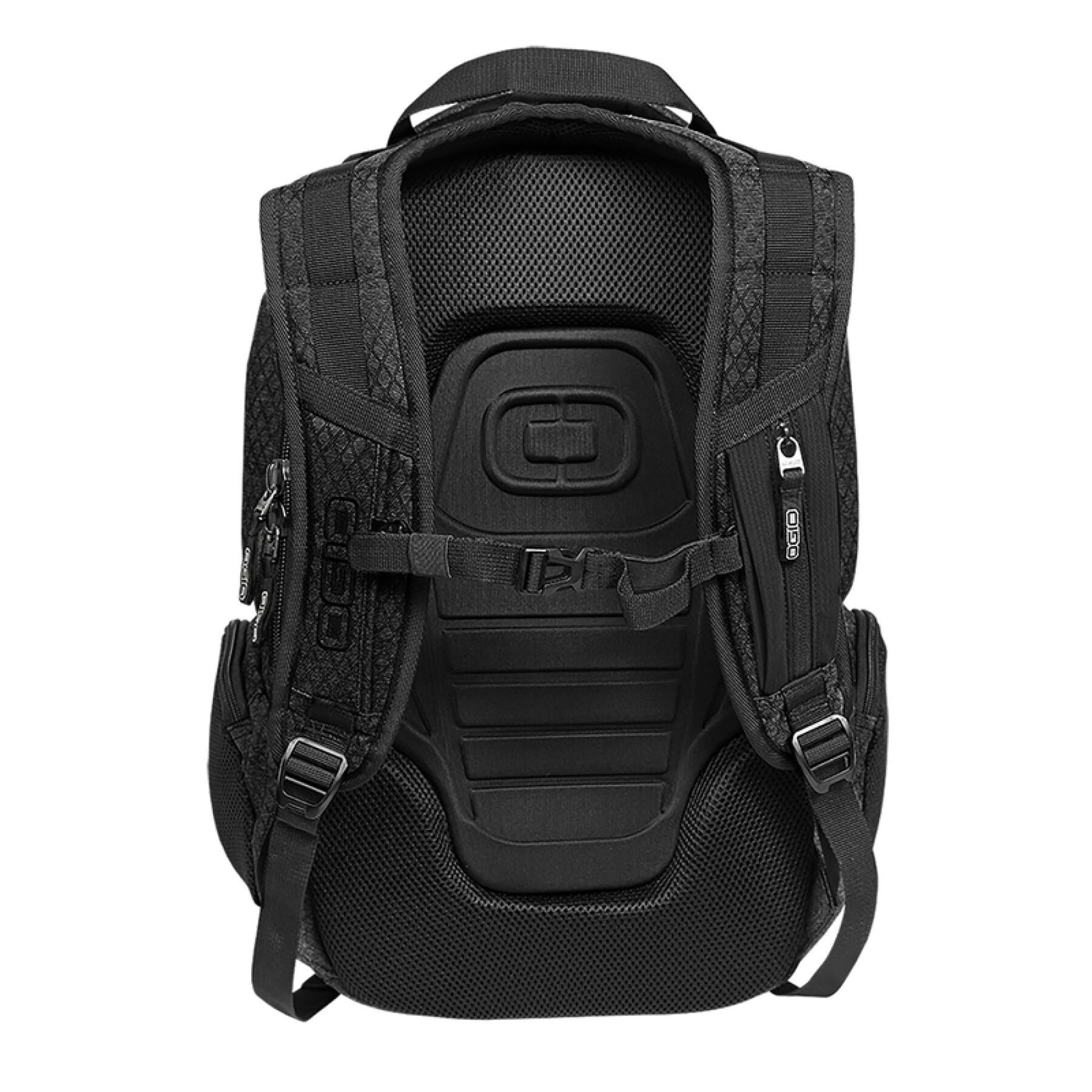 Mochila negra con malla y logo Ogio. Tiene múltiples correas y bolsillos. Visible desde la parte trasera.