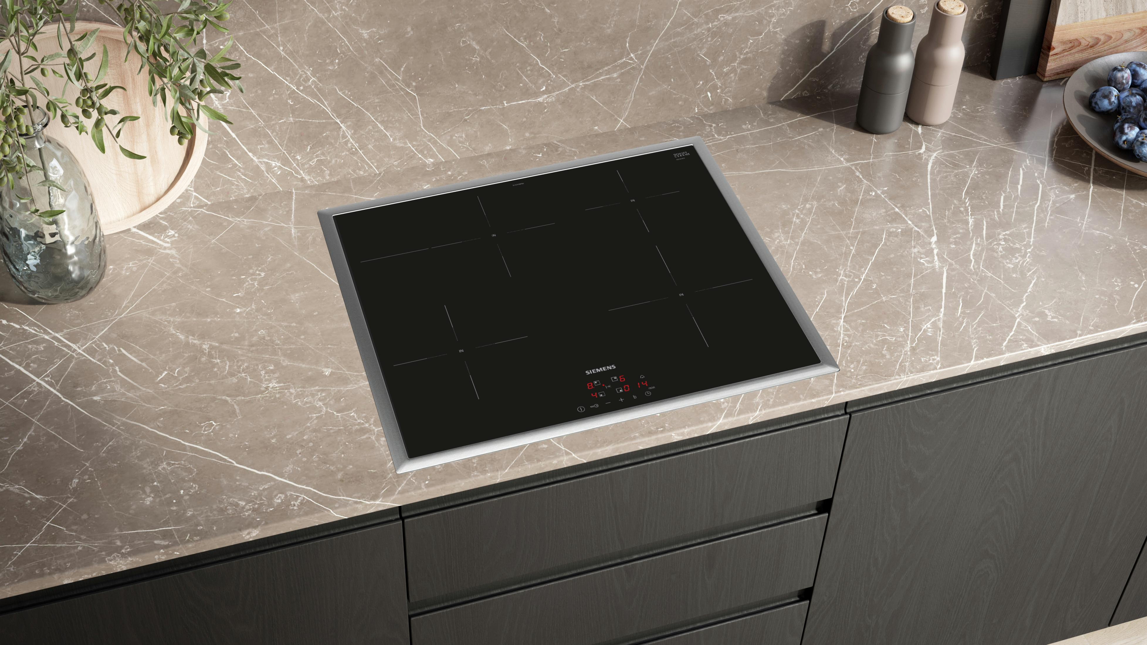 Czarna, wbudowana płyta indukcyjna na brązowym blacie, z czterema strefami gotowania i panelem dotykowym.