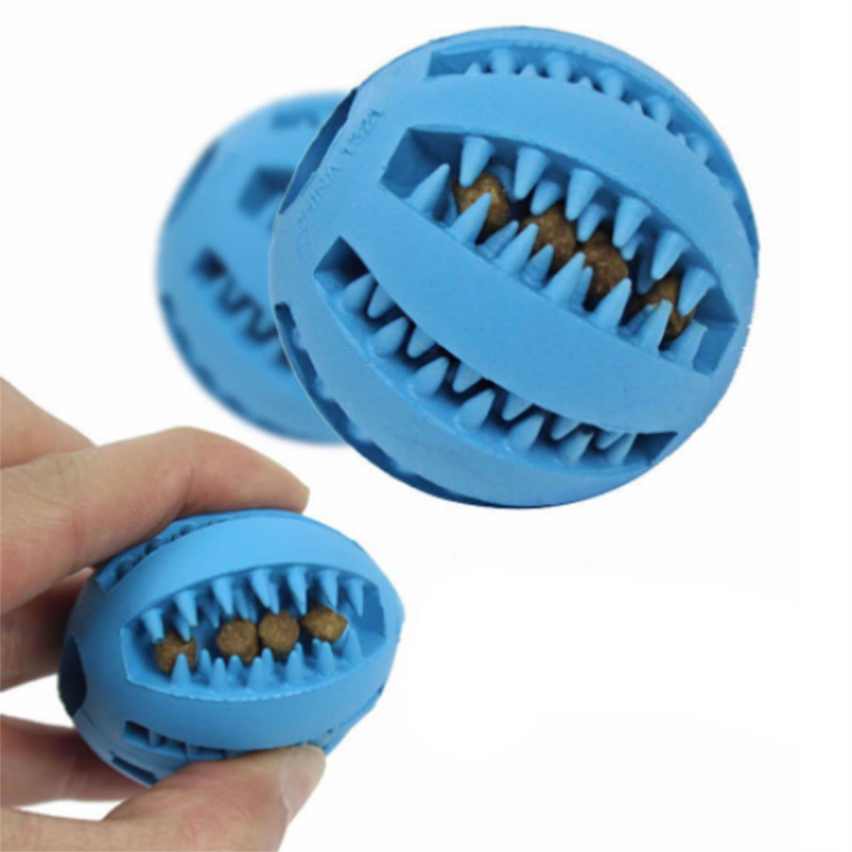 Blaue Hundespielzeugbälle mit zahnartigen Strukturen, die Leckerlis halten. Einer wird von einer Hand gehalten.