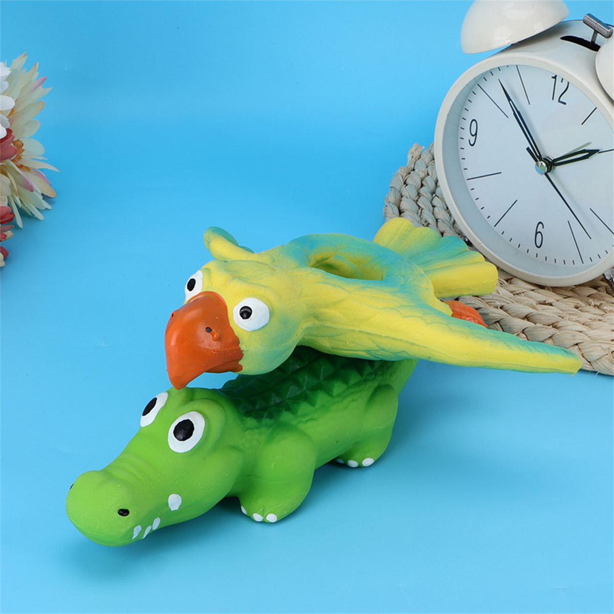 Ein Spielzeug mit einem Papagei auf einem Krokodil. Im Hintergrund ist eine Uhr.