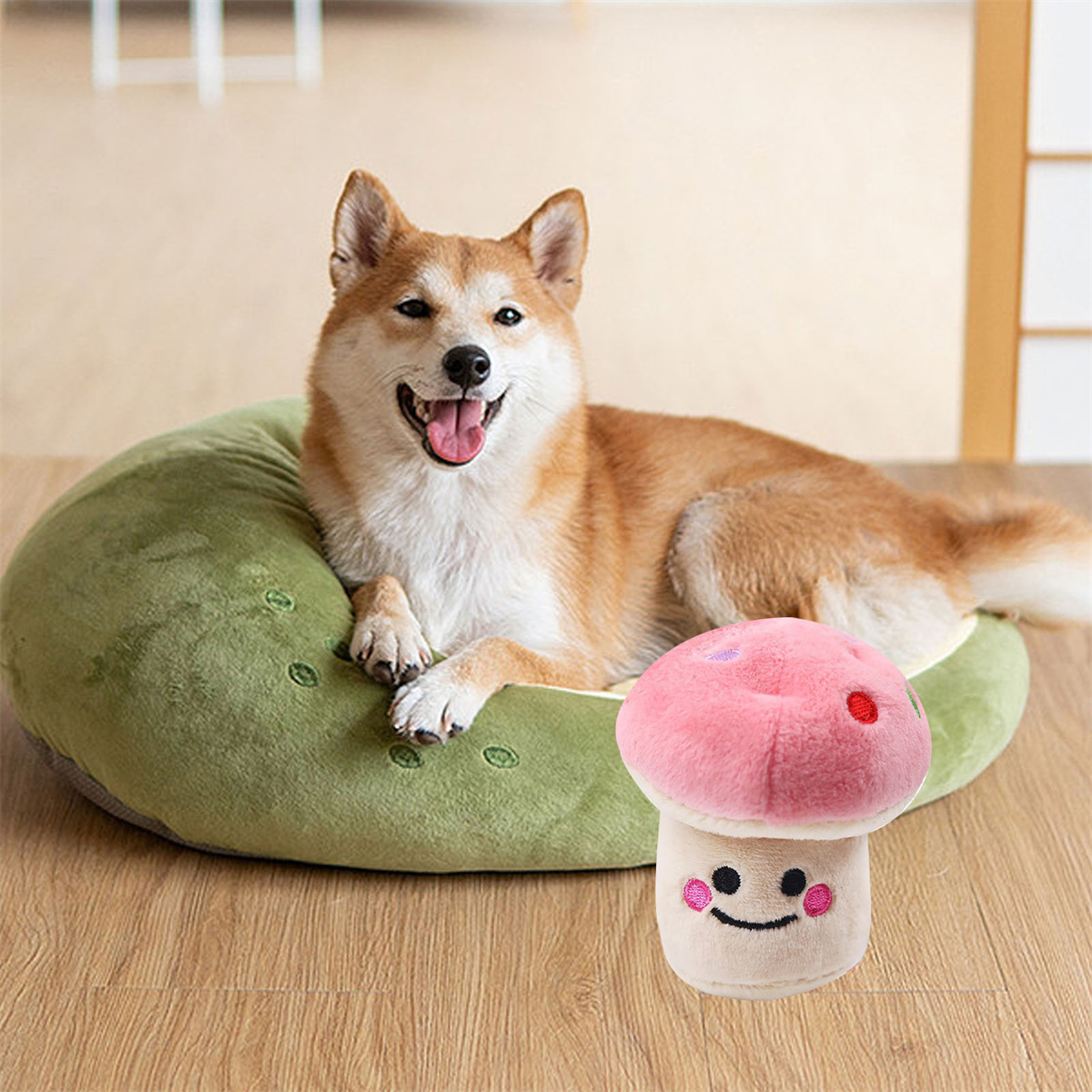 Ein Shiba Inu-Hund liegt auf einem grünen Bett neben einem Pilzspielzeug auf einem Holzboden.
