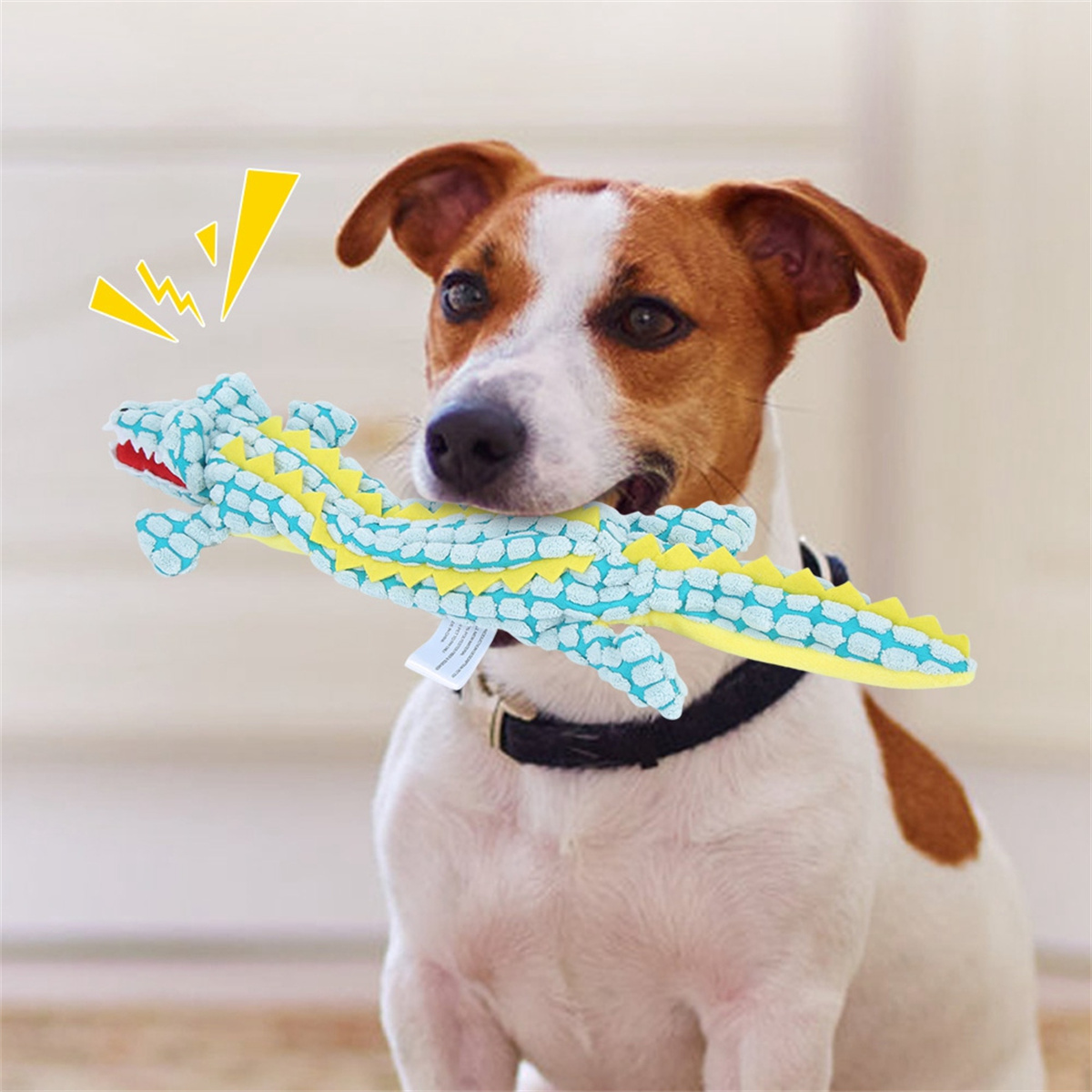 Hund hält ein blau-gelbes Alligator-Spielzeug im Maul, Sprechblase.