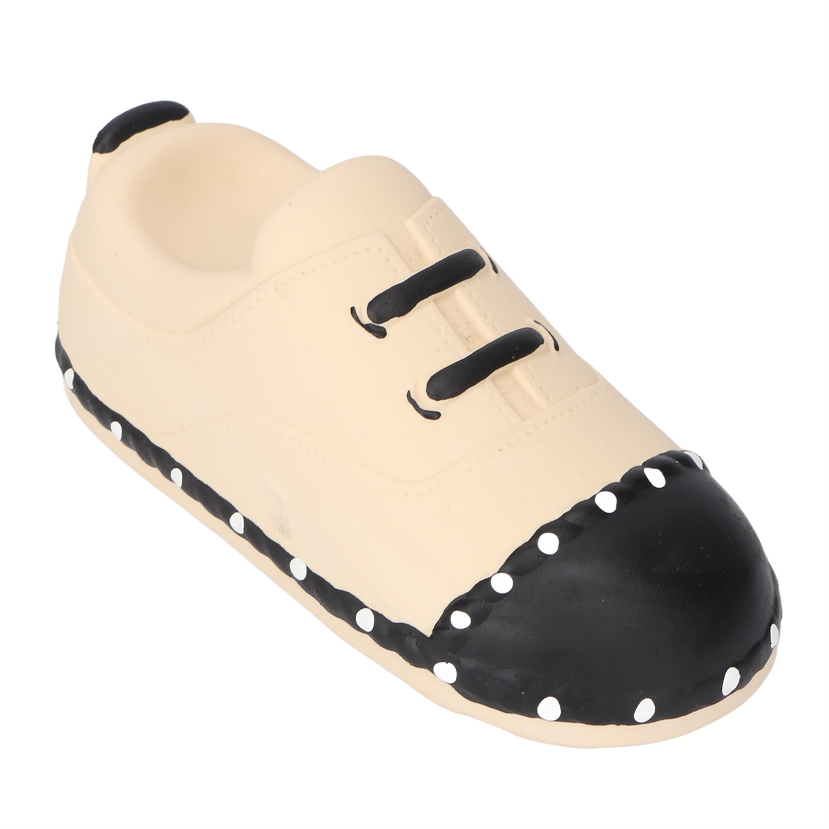 Spielzeugschuh, beige mit schwarzen Details. Schwarze Schnürsenkel und eine schwarze Zehenkappe mit weißen Punkten.
