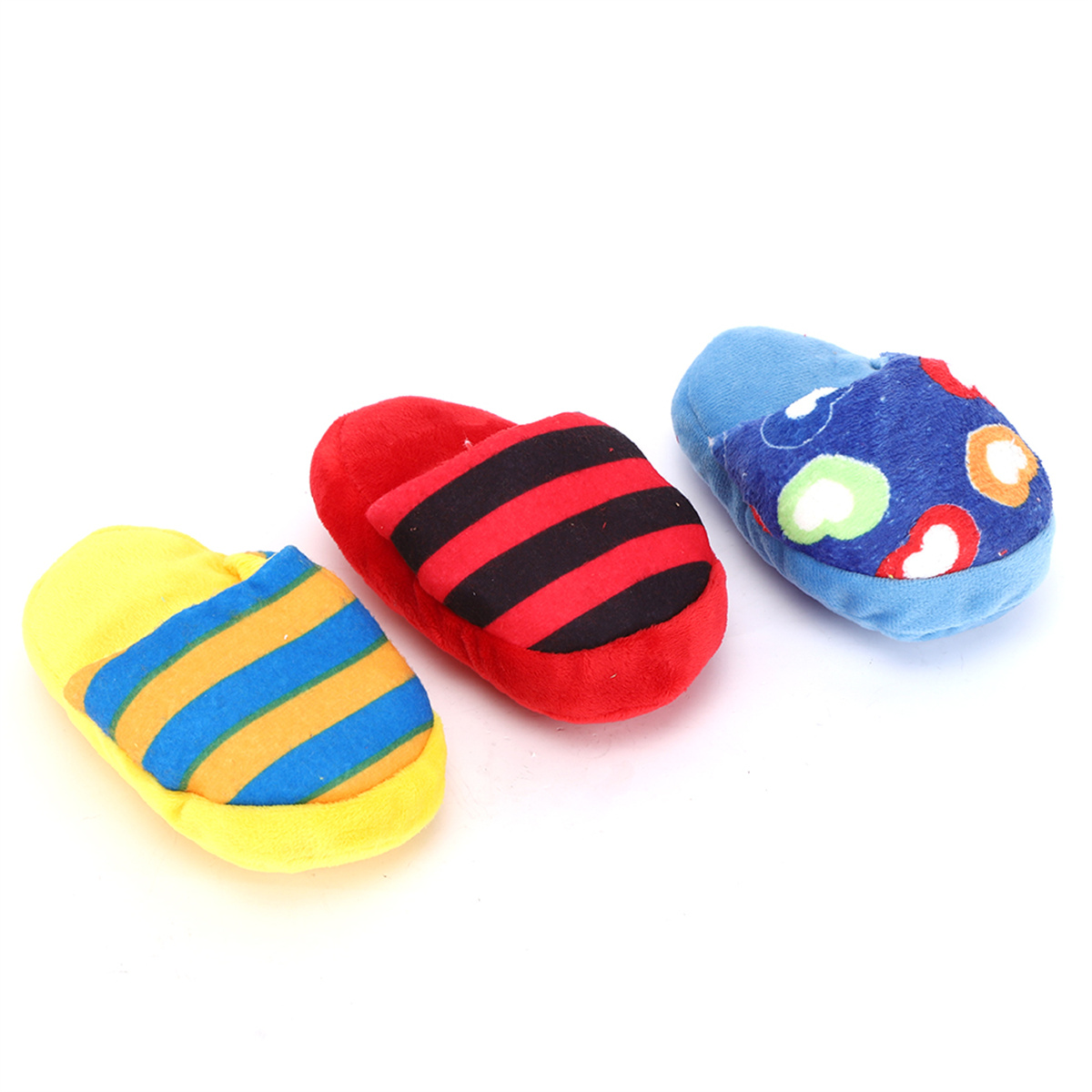 Drei Spielzeugslippers: gelb mit Streifen, rot mit schwarzen Streifen und blau mit Herzen, auf weißem Hintergrund.