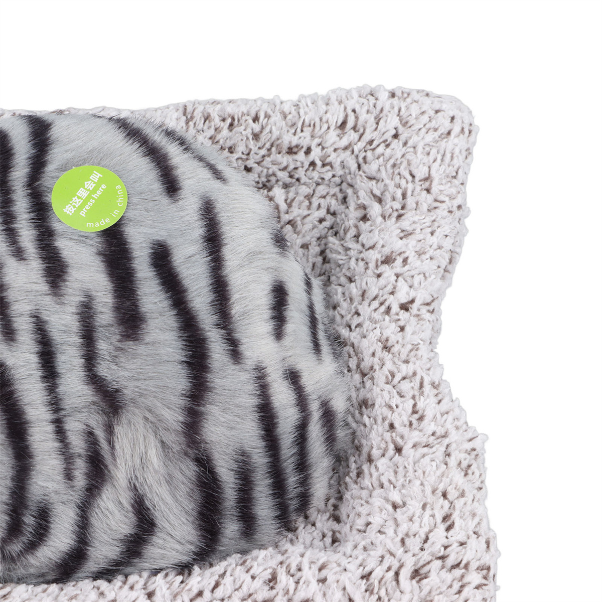 Nahaufnahme eines Katzenbettes mit einem grau-schwarz gestreiften Kissen auf einem flauschigen beigen Bett.