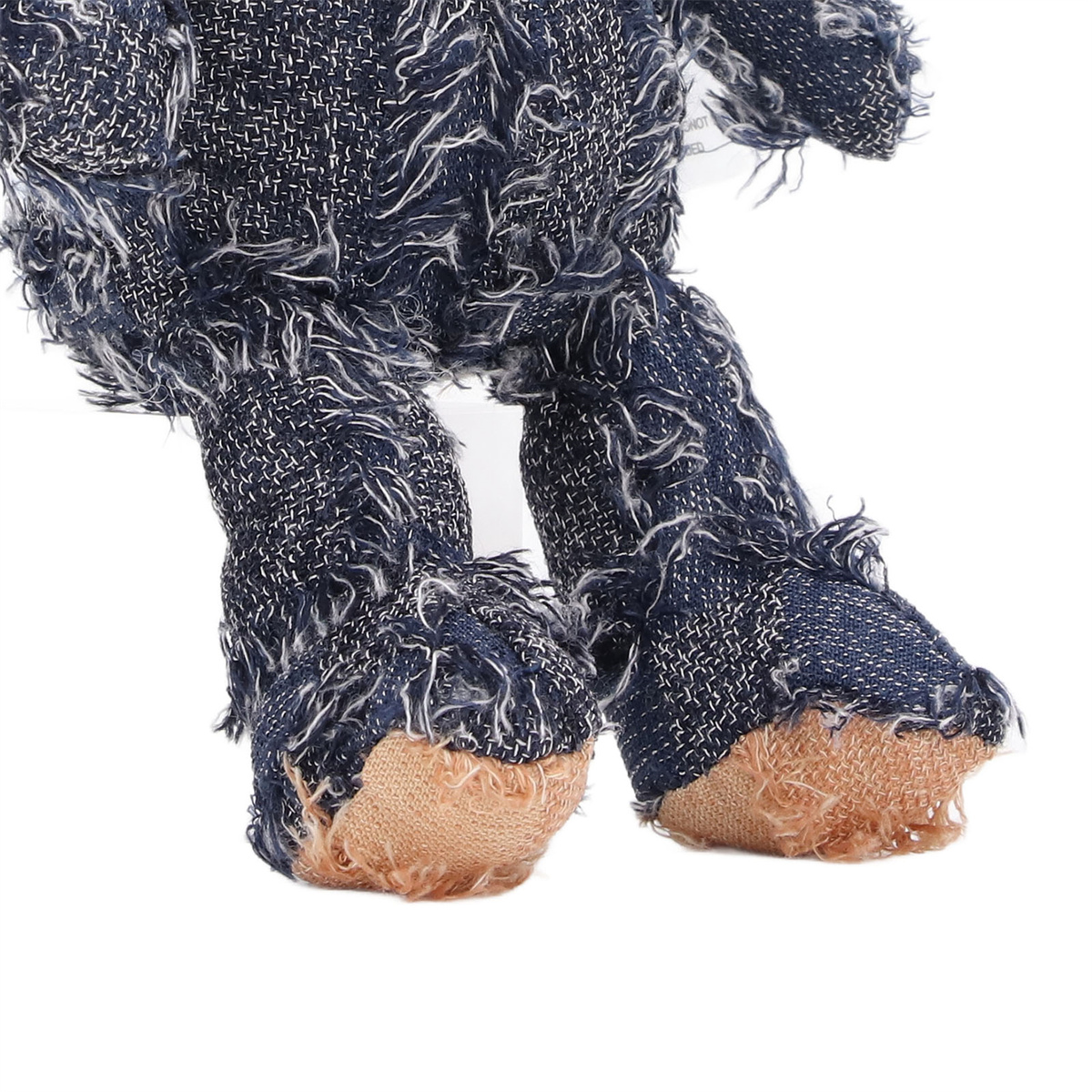 Ein Stofftier mit blauem, jeansartigem Material, das die Füße und Pfoten zeigt.