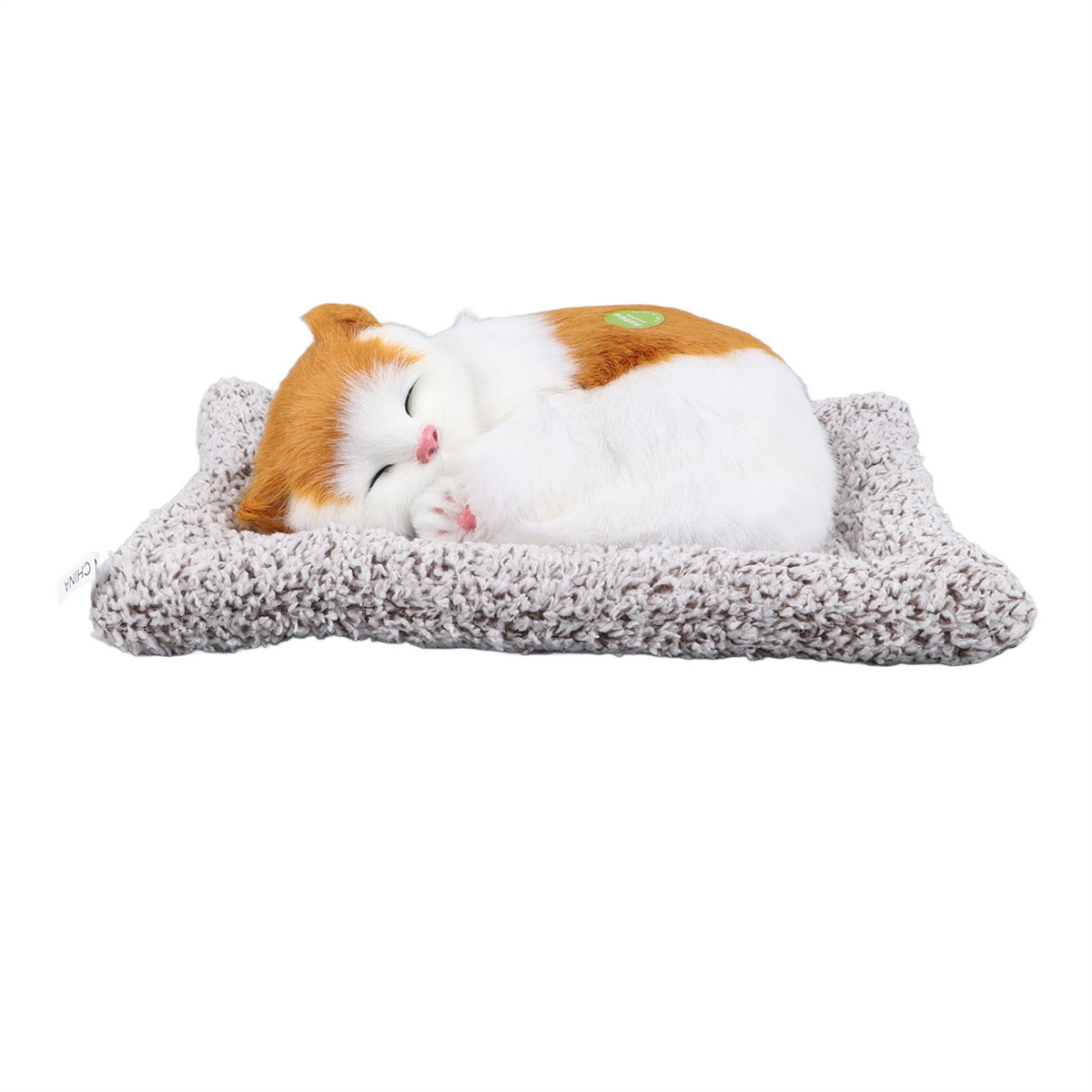 Ein schlafendes Katzenspielzeug auf einem strukturierten Kissen. Orange und weiße Katze mit geschlossenen Augen.