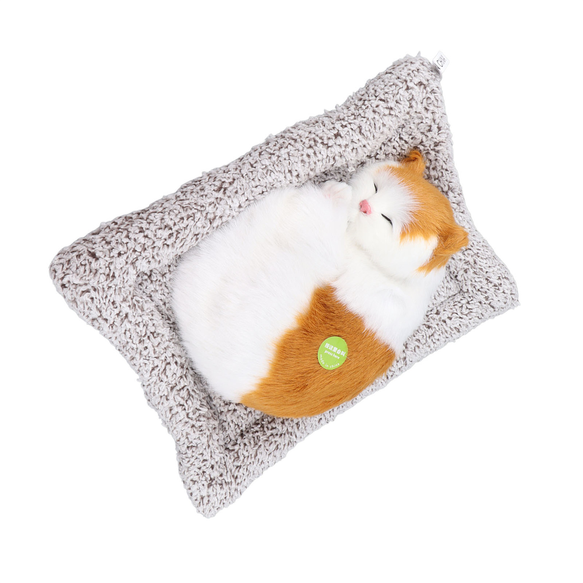 Katzen-Spielzeug in einem Bett. Die Katze ist weiß und orange, schläft.