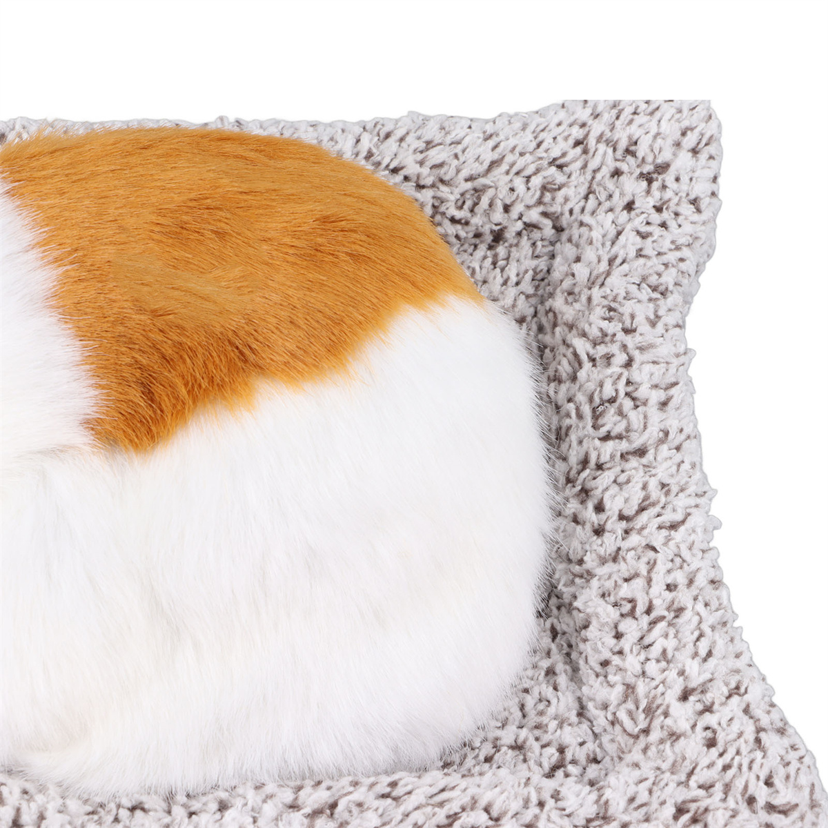 Eine rot-weiße Katze, die sich auf einem grauen Plüschbett zusammenrollt.