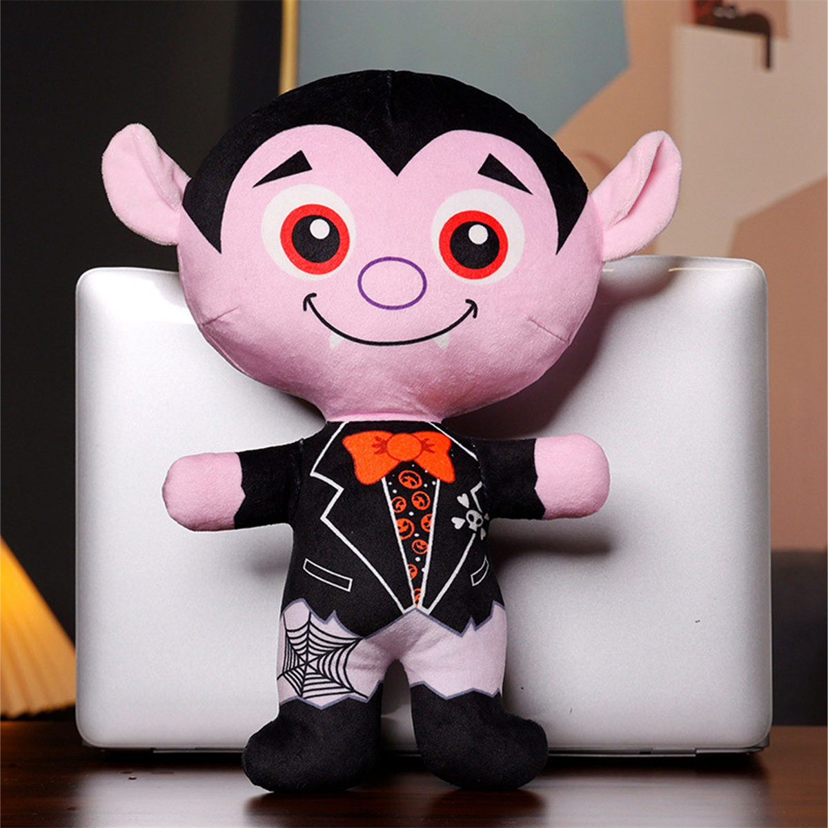 Eine Plüschpuppe eines Vampirs mit schwarzem Anzug und rosa Gesicht, die auf einer weißen Oberfläche steht.