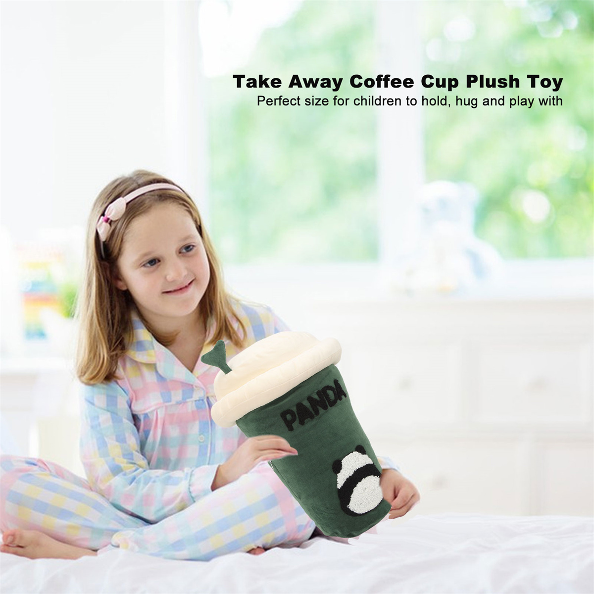Ein Mädchen hält eine Plüsch-Kaffeebecher-Spielzeug, sitzt auf einem Bett mit weißem Hintergrund.