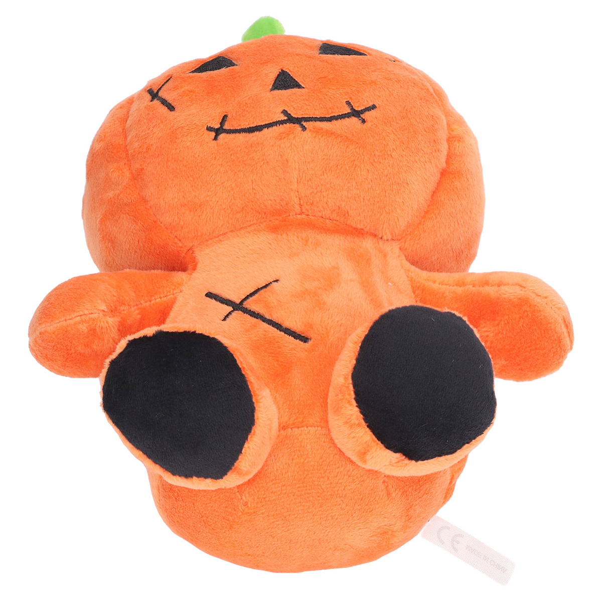 Oranges Plüsch-Kürbis-Spielzeug mit schwarzen Gesichtsdetails und schwarzen Füßen, liegend.