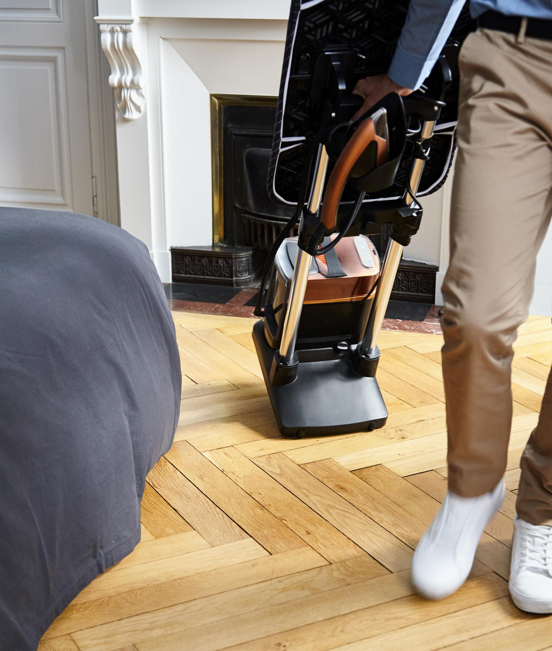 Osoba tocząca czarny i srebrny system prasowania po drewnianej podłodze.