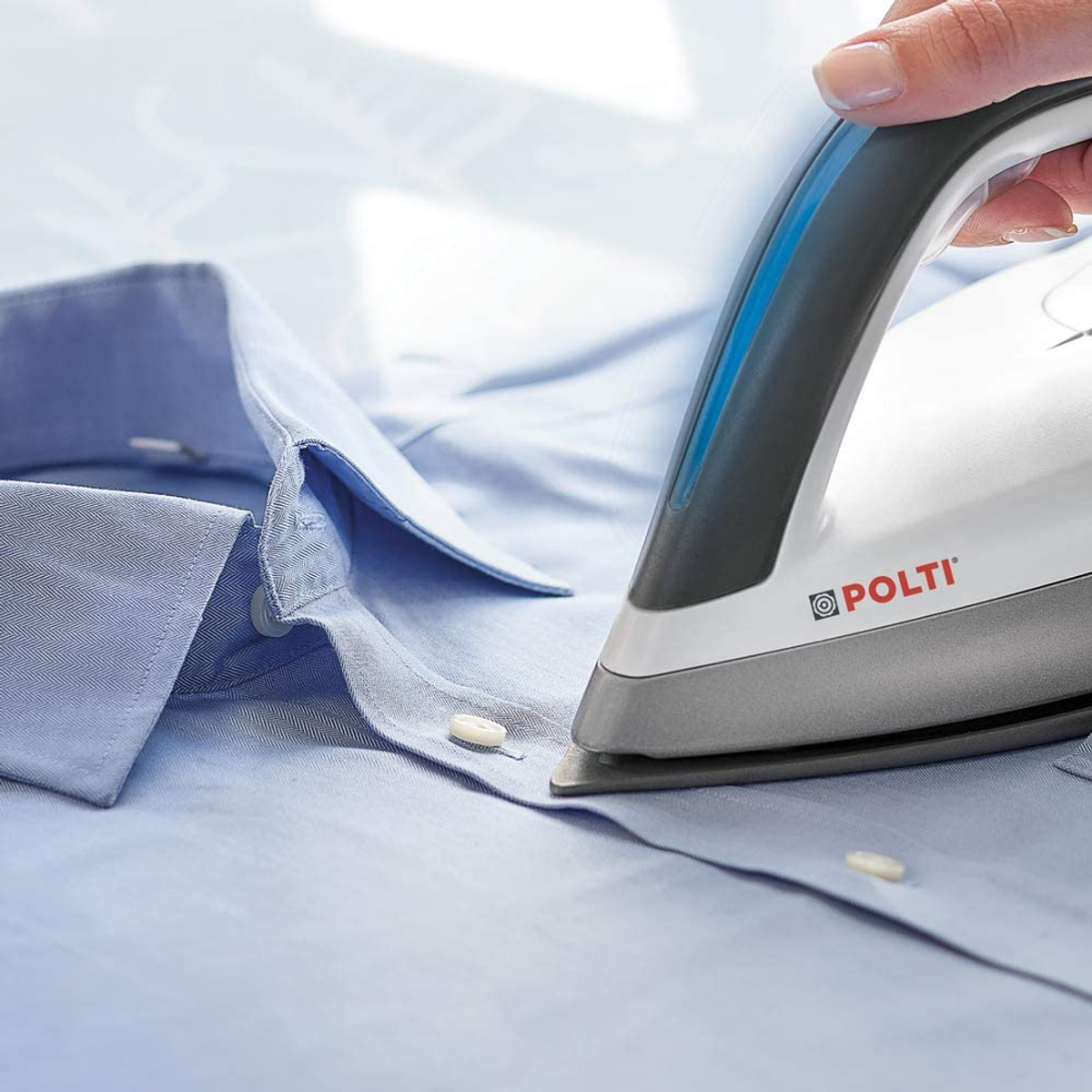 Una persona che stira una camicia blu con un ferro da stiro bianco. Il ferro è etichettato 'POLTI'.