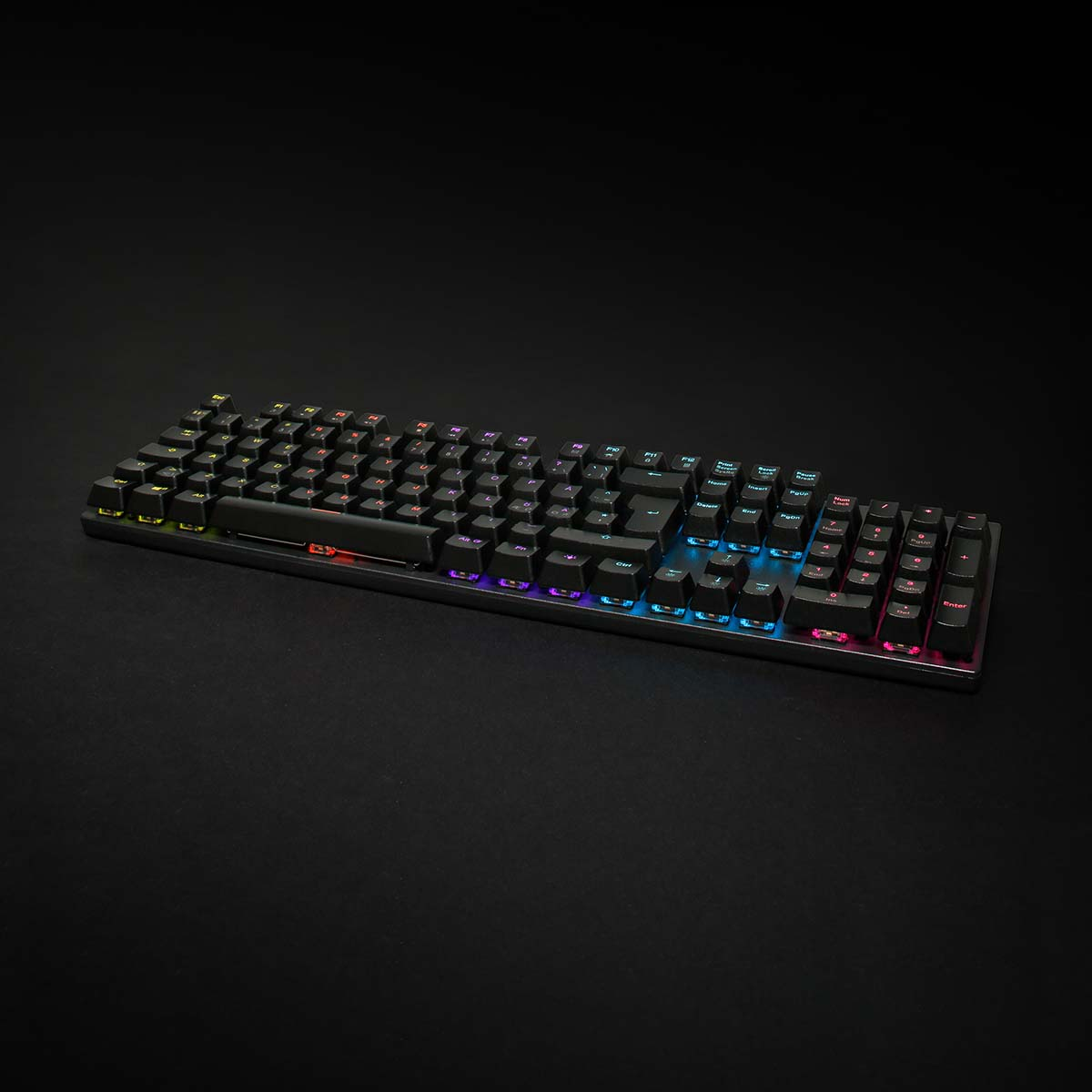 Czarna klawiatura mechaniczna z kolorowymi klawiszami. Podświetlane klawisze, czarne tło.