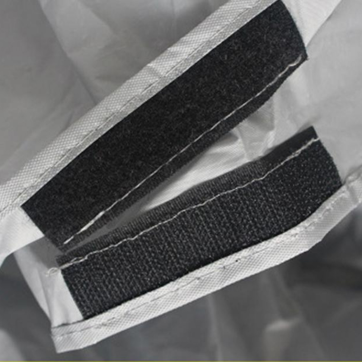 Weißes Material mit zwei Klettbändern. Die Bänder sind dunkelgrau.