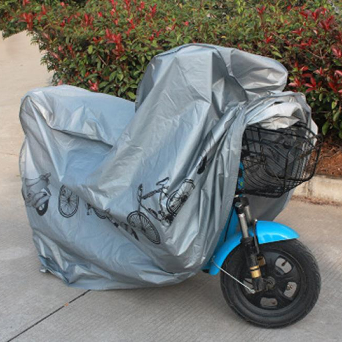 Ein blauer Roller wird von einer grauen Hülle mit Fahrradaufdruck bedeckt.