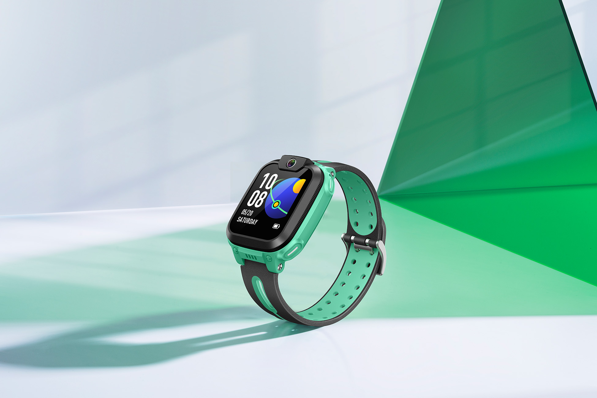 Uno smartwatch su una superficie bianca, cinturino verde, schermo nero e una fotocamera. Sfondo verde e bianco.