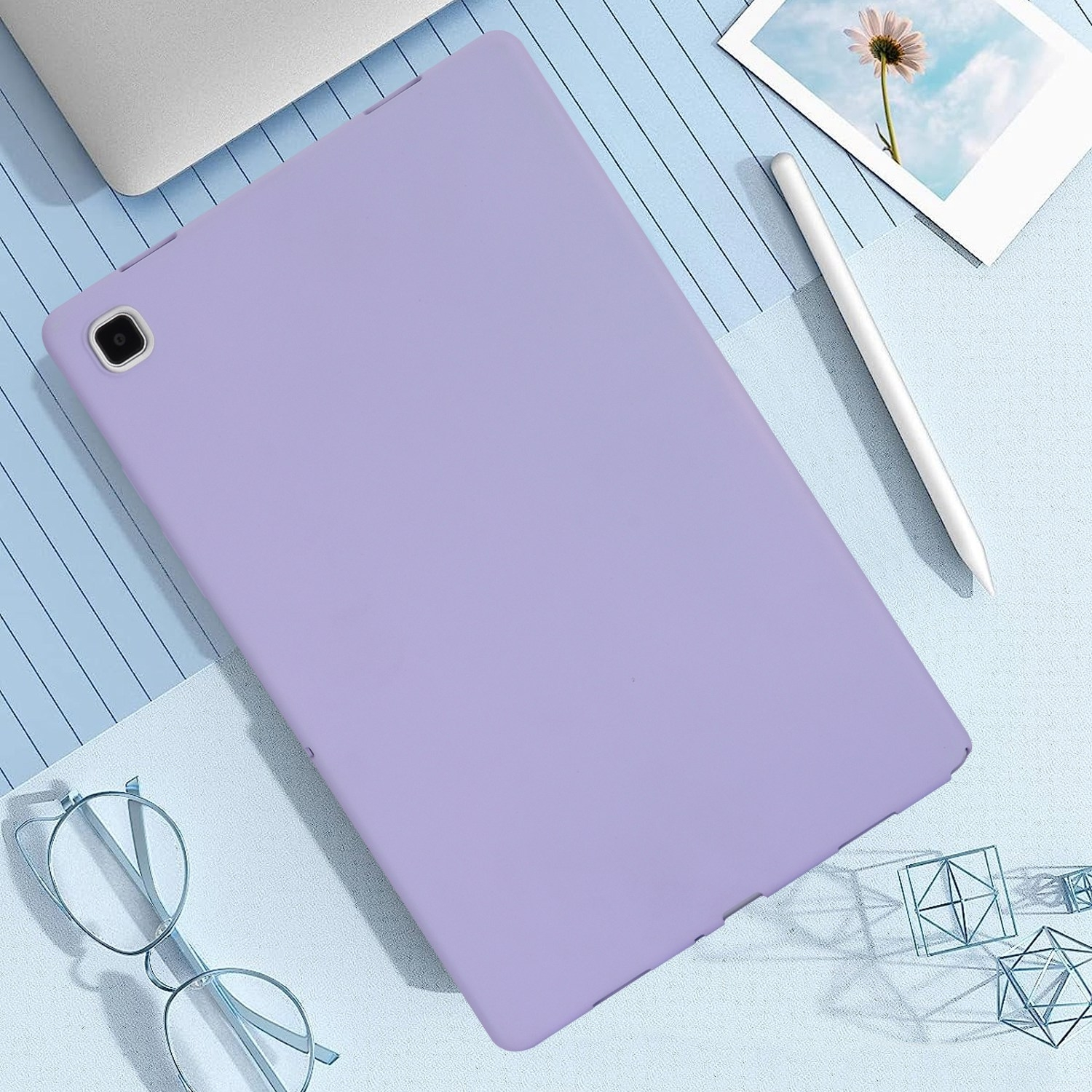 Ein lila Tablet liegt auf einer blauen Oberfläche mit einem Stift, einer Brille und geometrischen Formen.