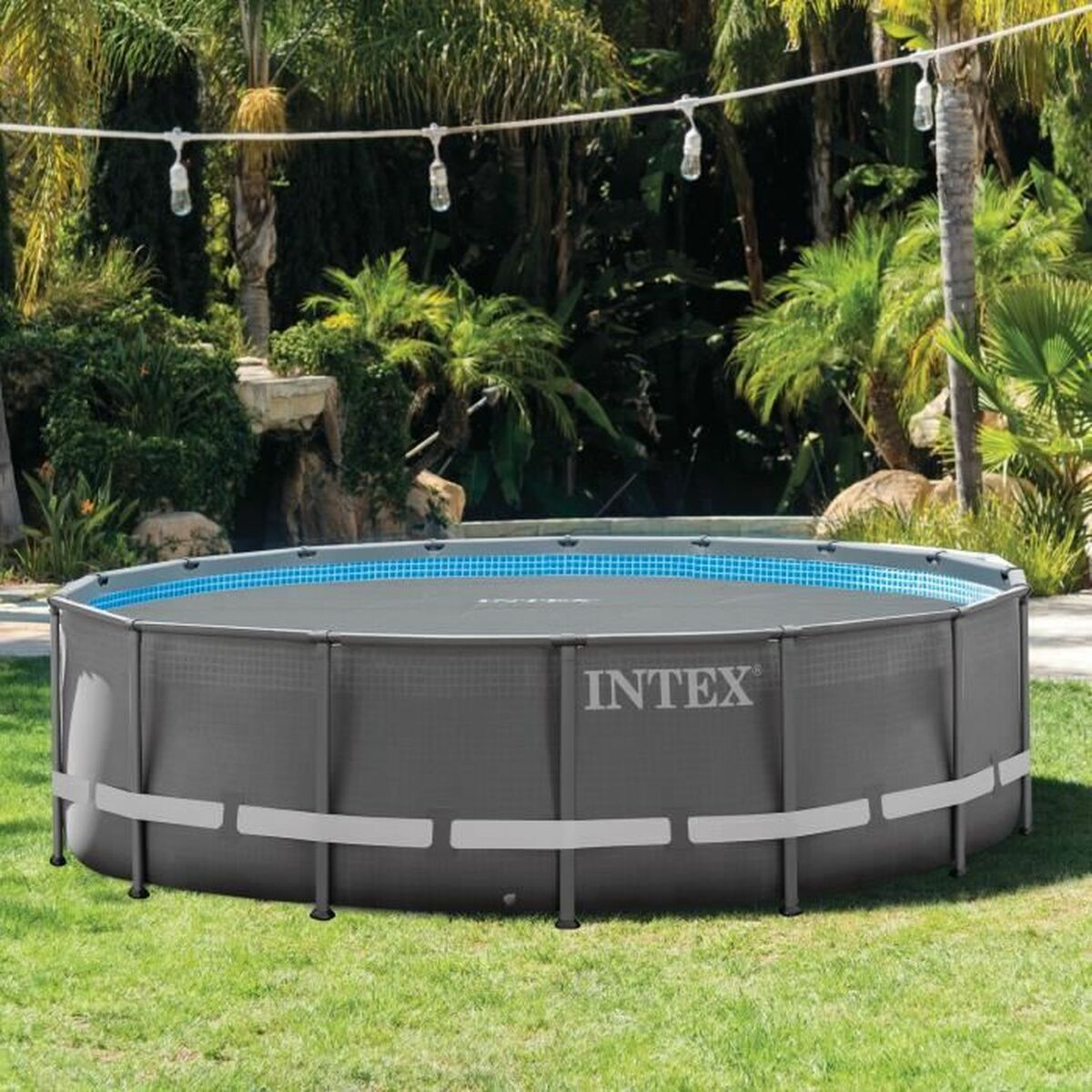 Ein oberirdischer Pool in einem Garten mit Gras, umgeben von einem niedrigen Zaun und Pflanzen.