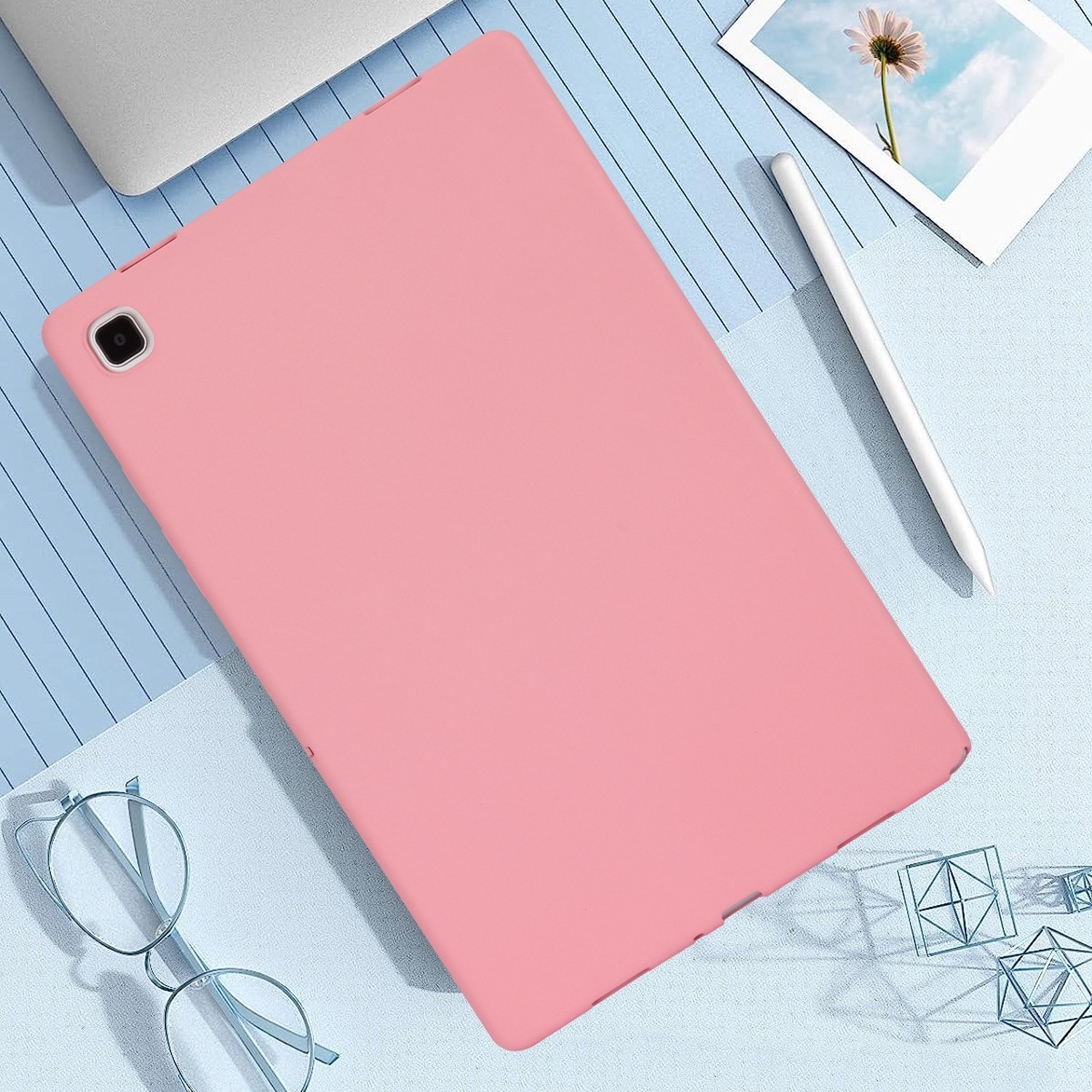 Rosa Tablet auf blauer Oberfläche mit Stift, Brille und geometrischen Formen.