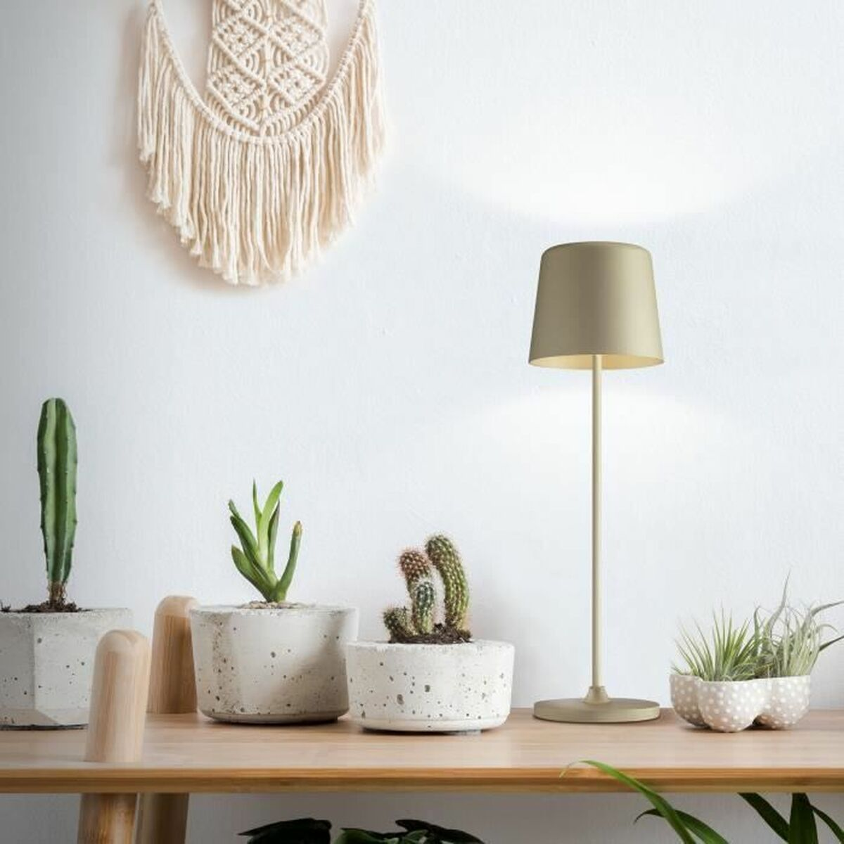 Ein Holztisch hat Pflanzen und eine Lampe. Oben befindet sich ein Makramee-Wandbehang.