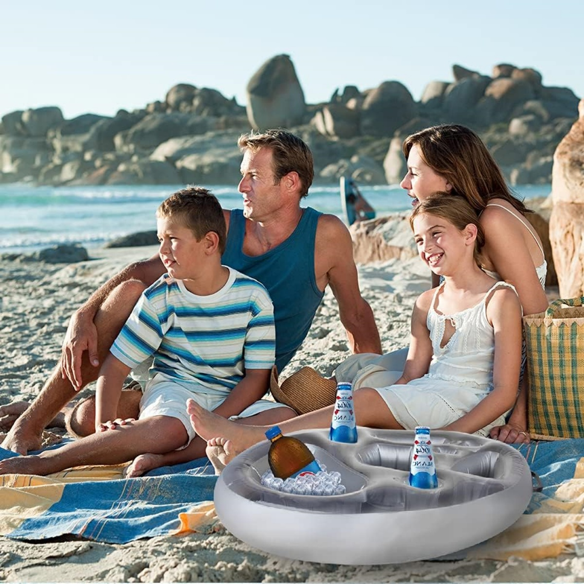 Eine Familie am Strand mit einer schwimmenden Kühlbox im Vordergrund. Menschen und Ozean sichtbar.
